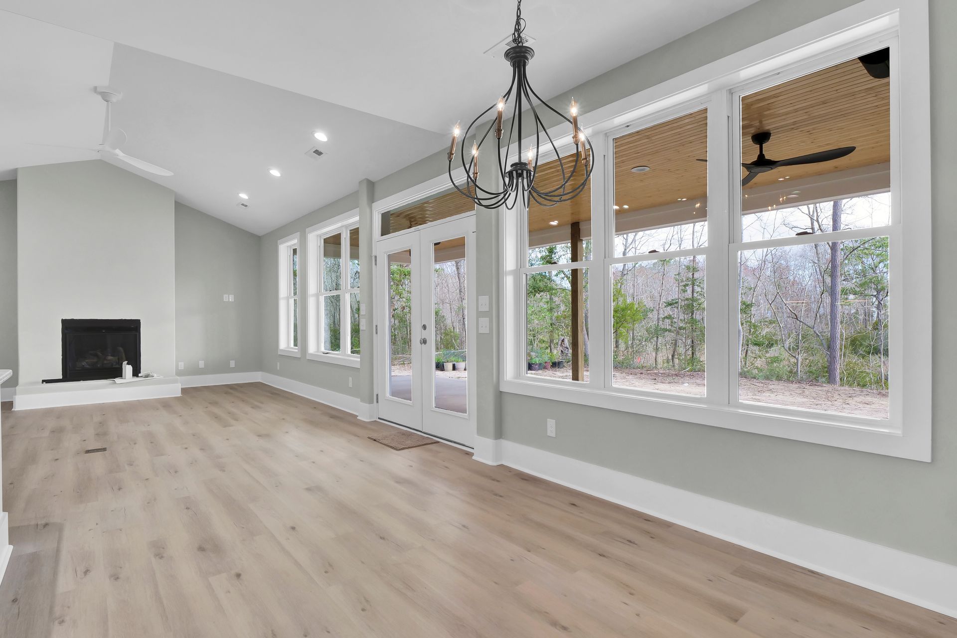 An empty living room with lots of windows and a fireplace.