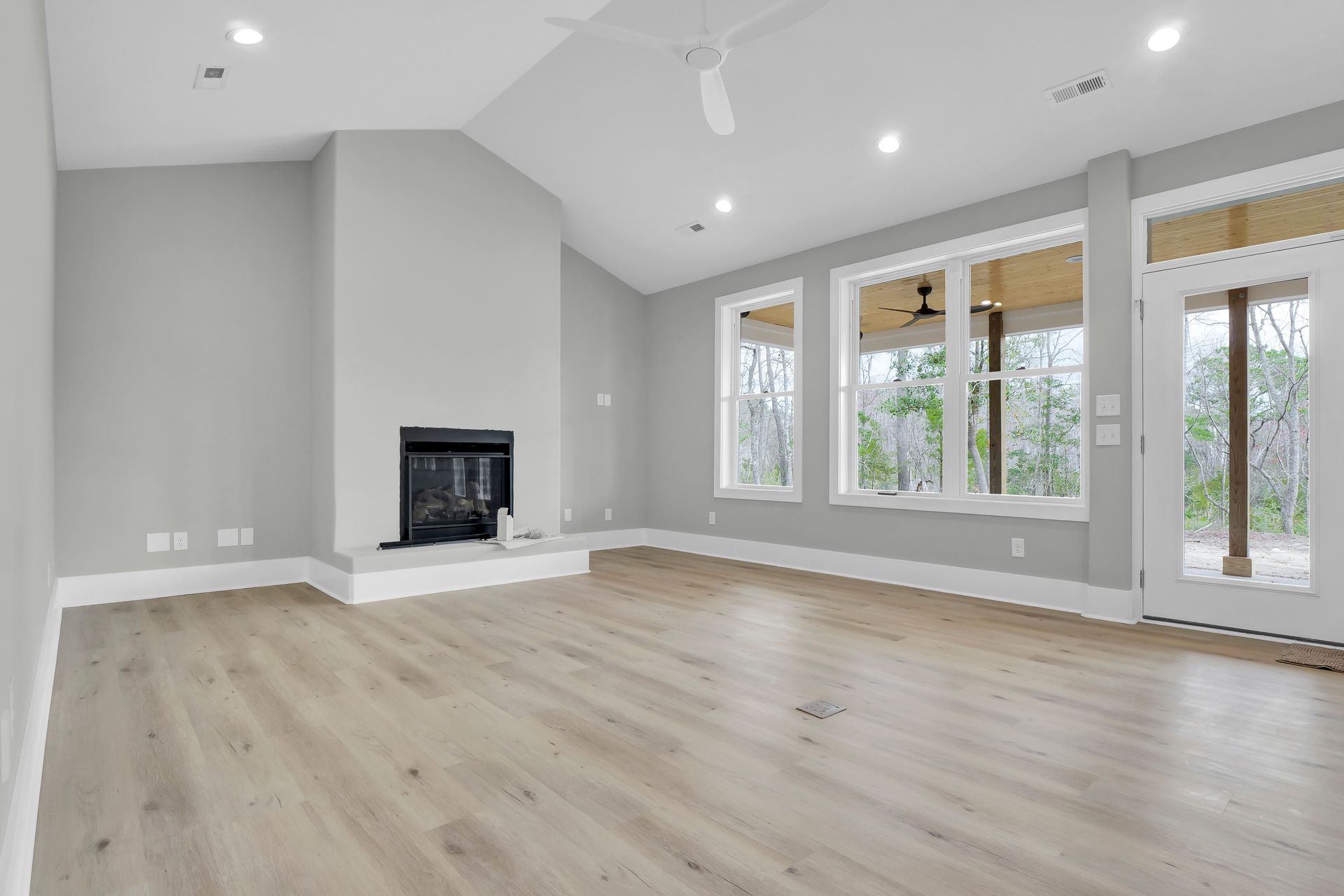 An empty living room with hardwood floors and a fireplace.