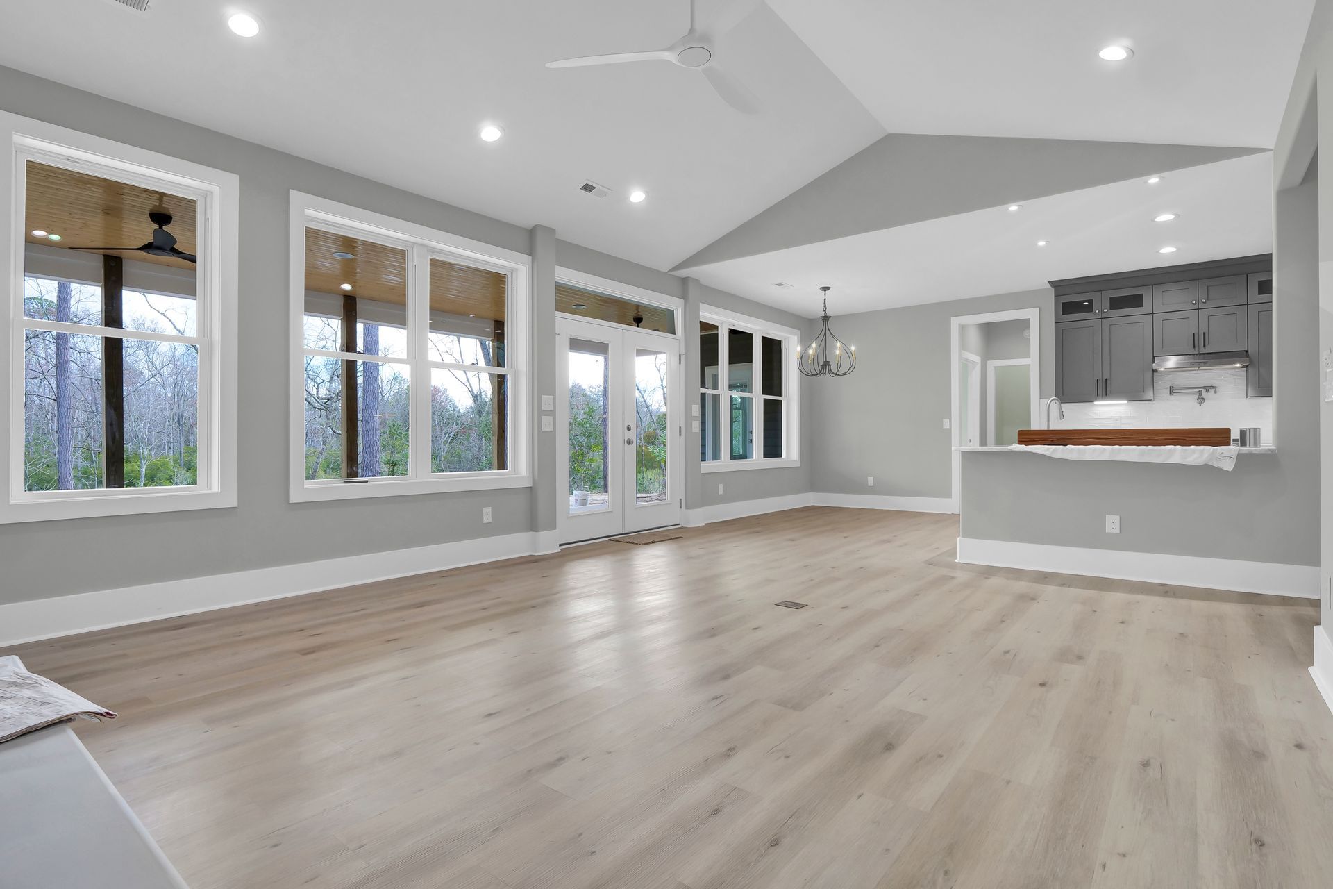 A large empty living room with hardwood floors and a ceiling fan.