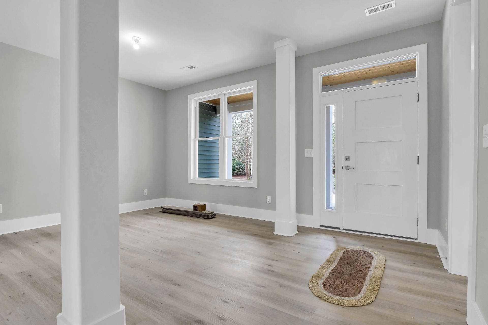 An empty living room with hardwood floors and a white door.
