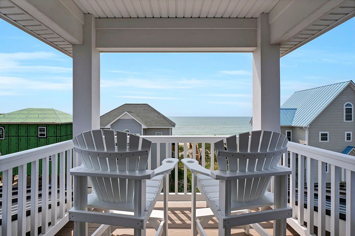 A balcony with two chairs and a view of the ocean
