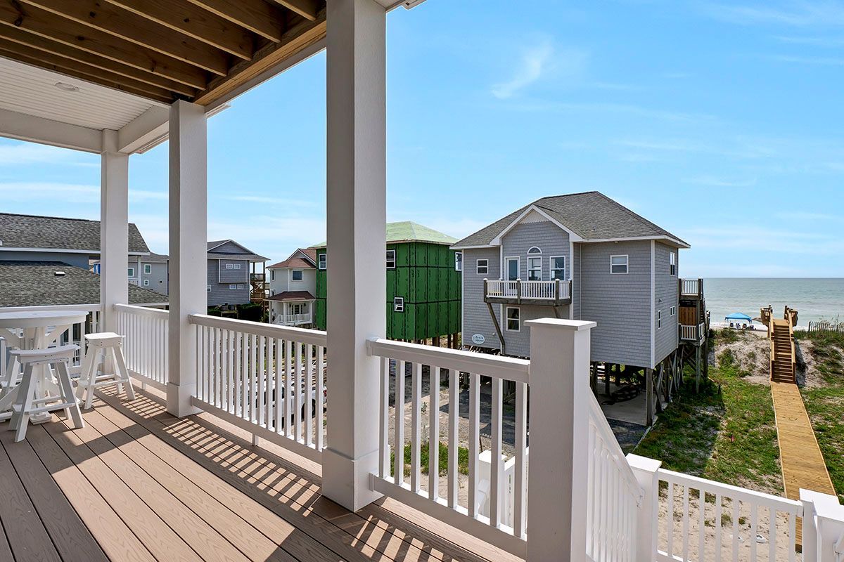 A balcony with a view of a house and the ocean