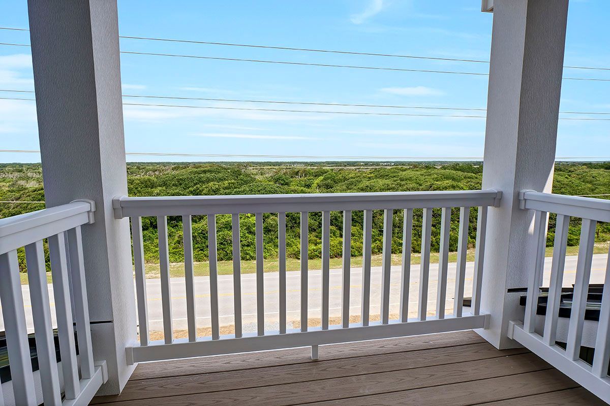 A balcony with a view of the ocean and trees