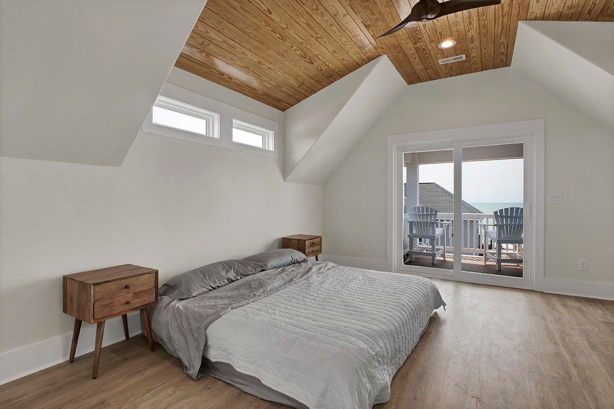 A bedroom with a large bed and a balcony overlooking the ocean