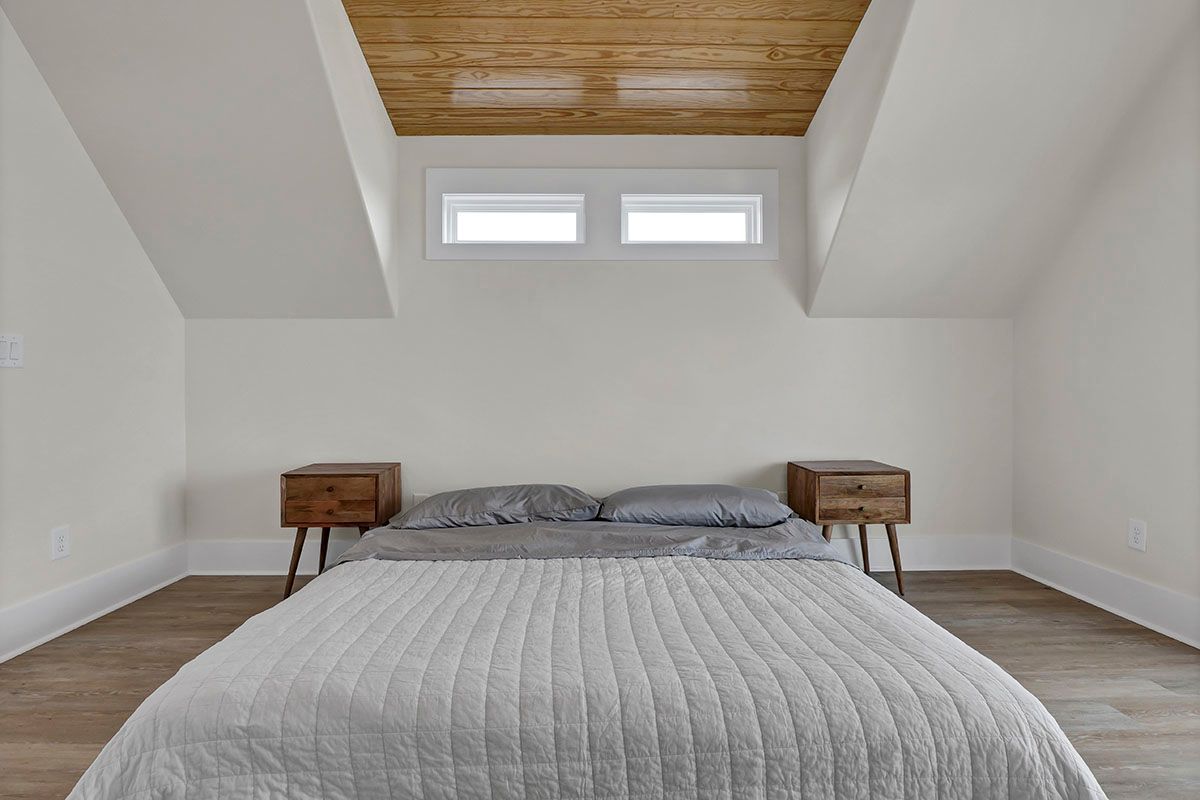 A bedroom with a bed, two nightstands, and a wooden ceiling