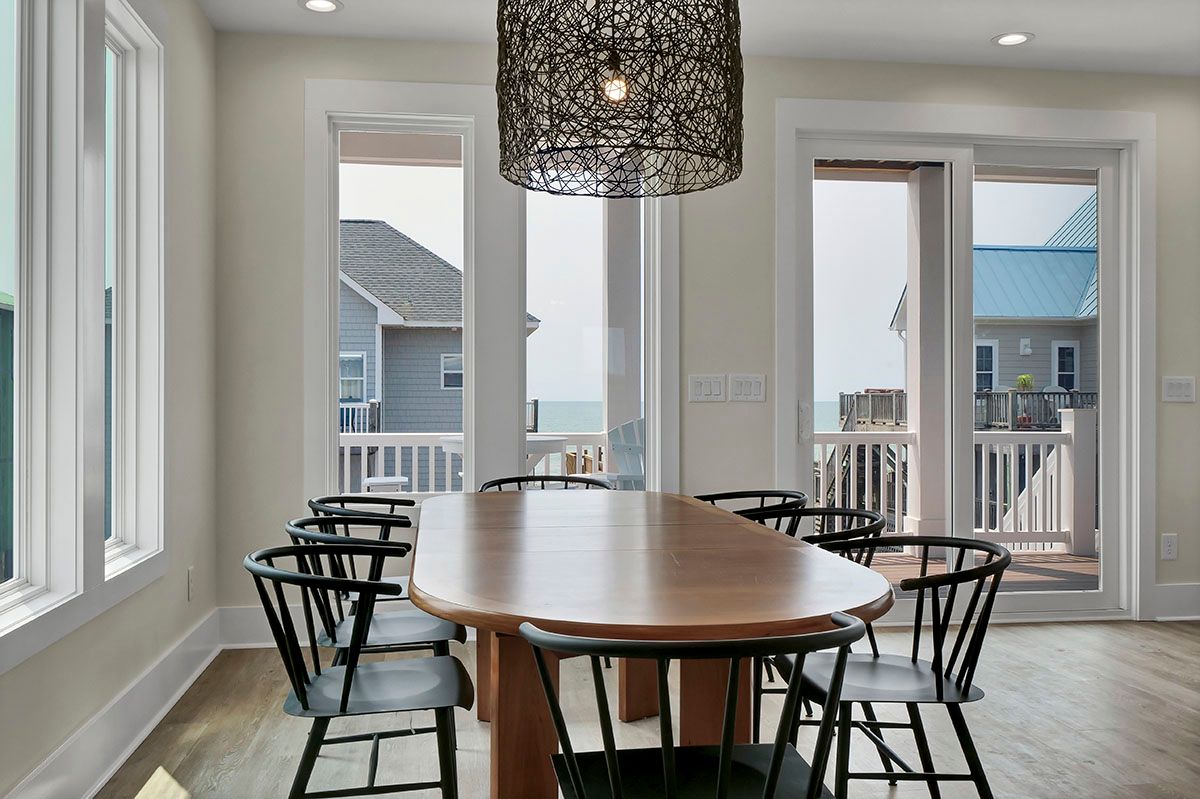 A dining room with a table and chairs and a view of the ocean