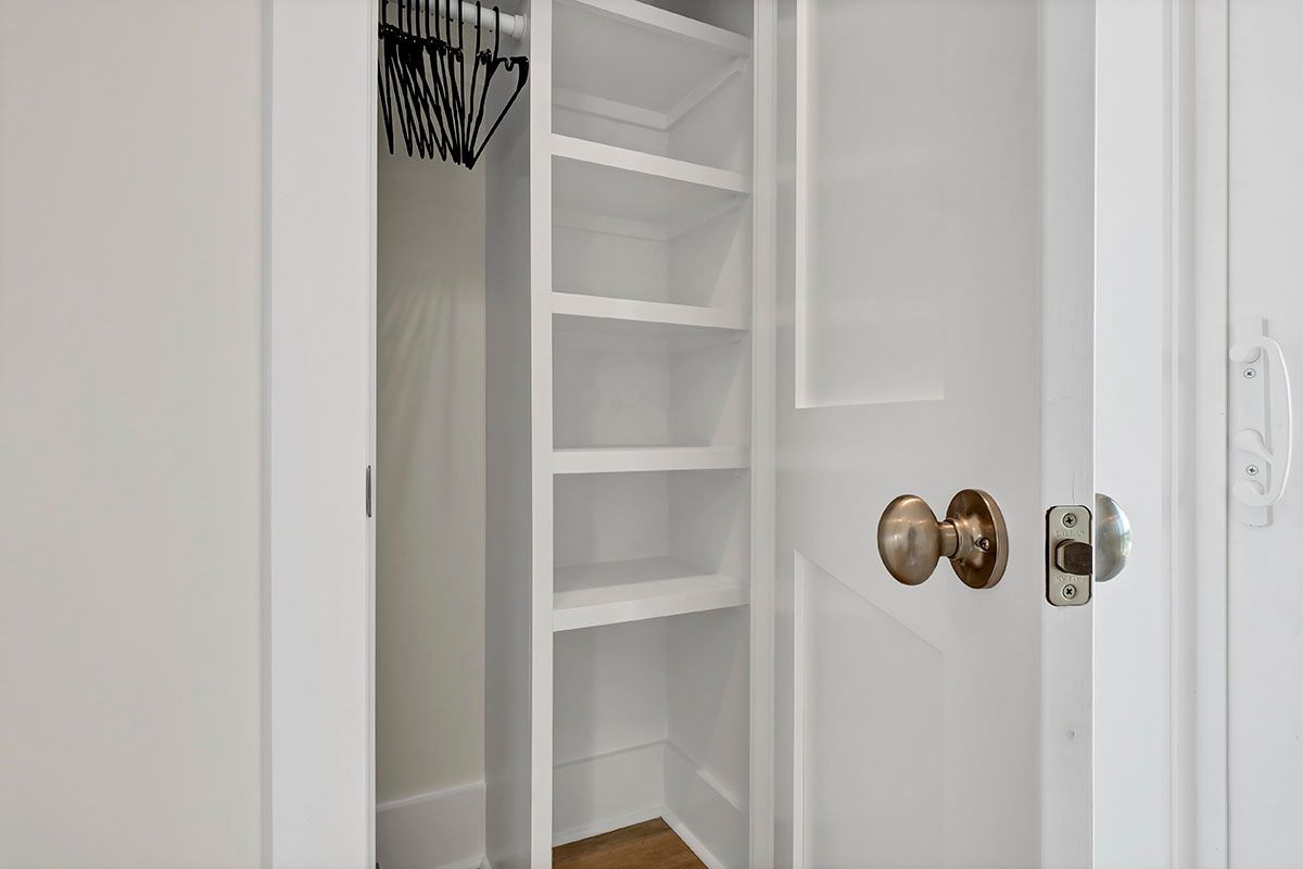 A white closet with shelves and a door