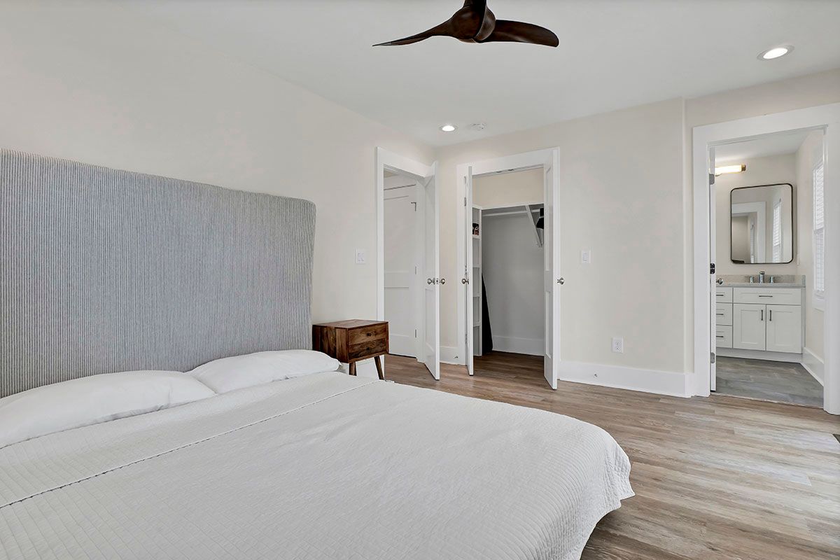 A bedroom with a bed, nightstand, and ceiling fan