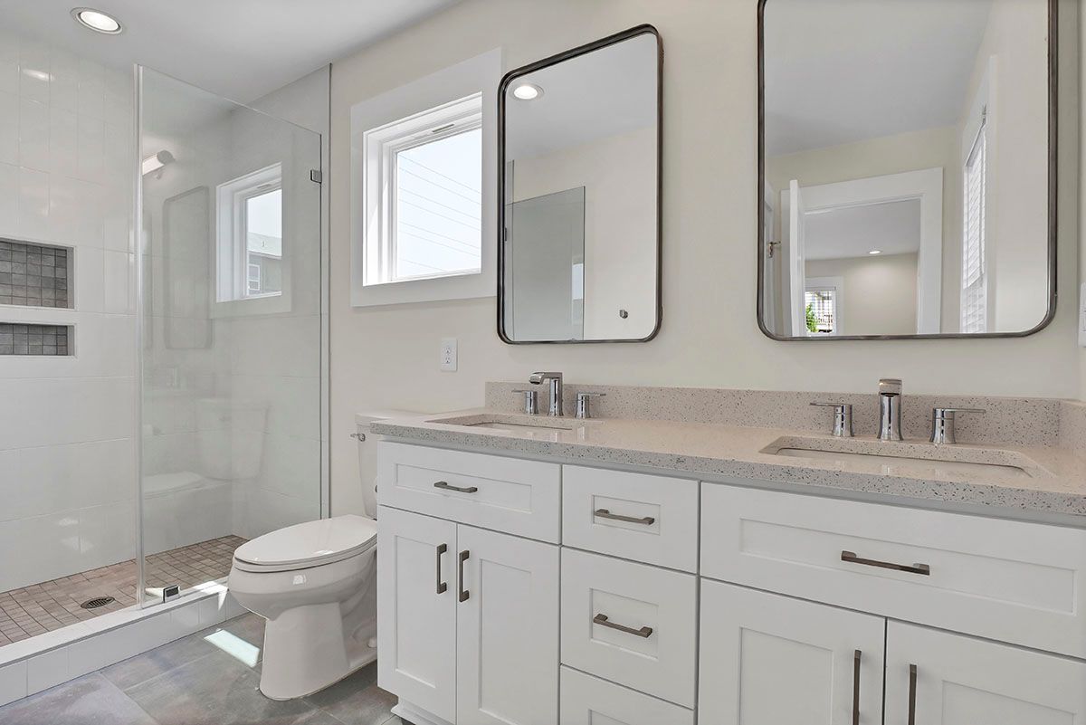 A bathroom with two sinks, a toilet, and mirrors
