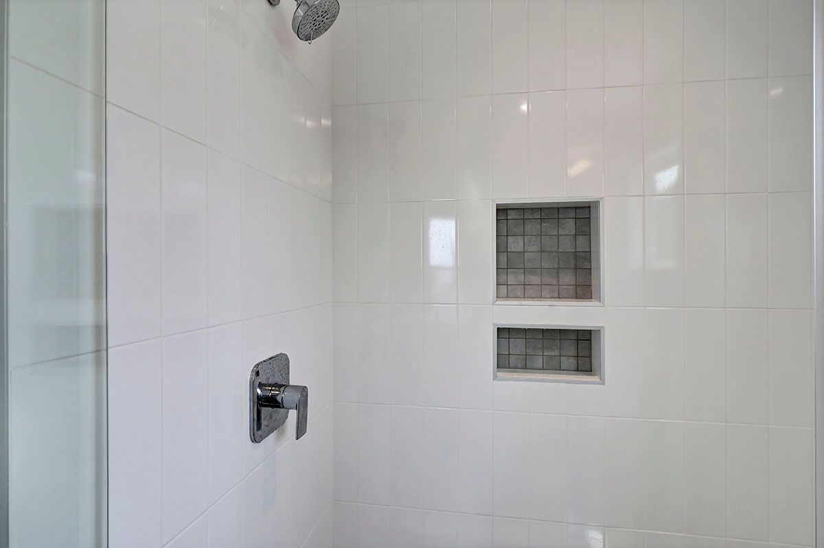 A bathroom with white tiles and a walk-in shower