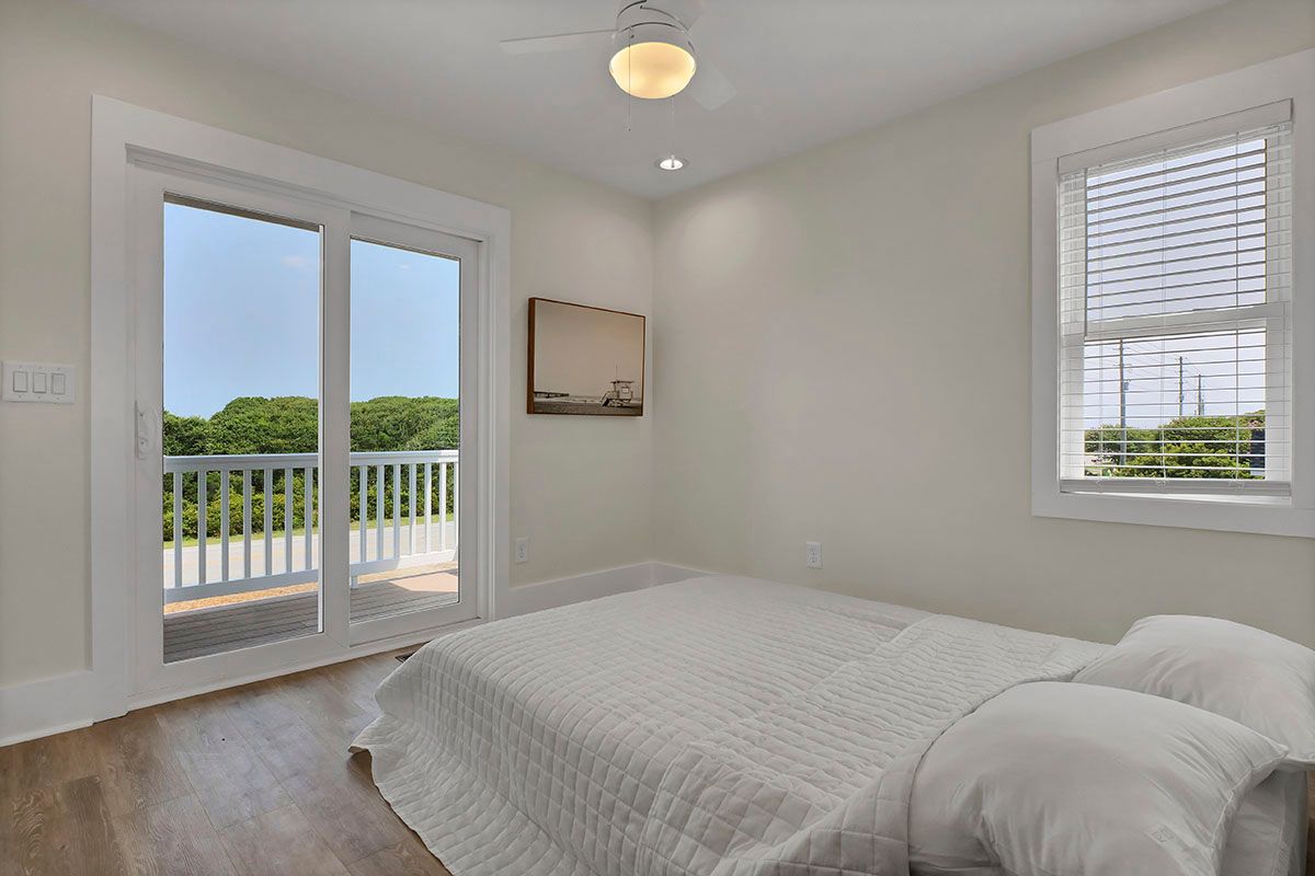 A bedroom with a bed, two windows, and a ceiling fan