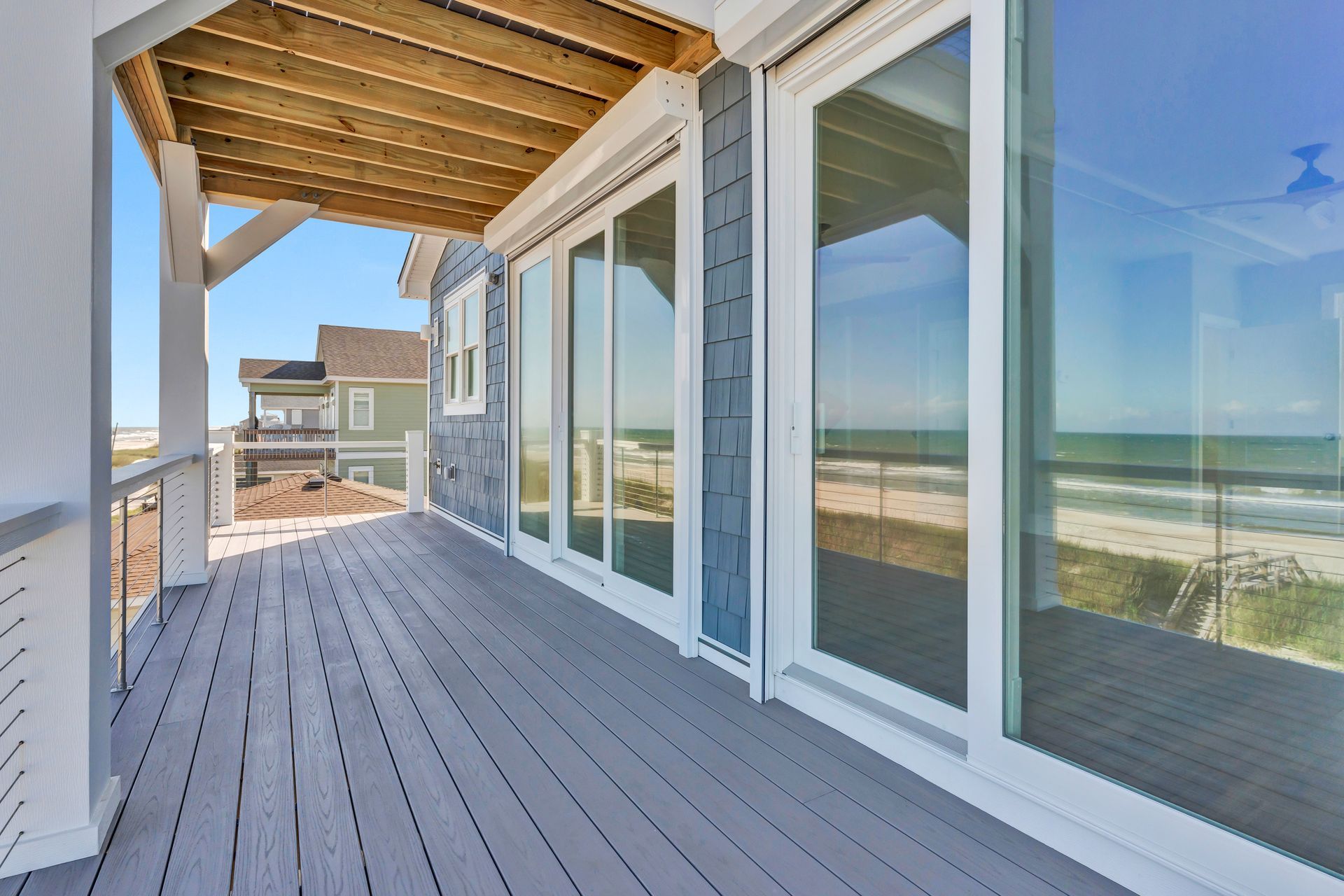 A large deck with sliding glass doors and a view of the ocean.