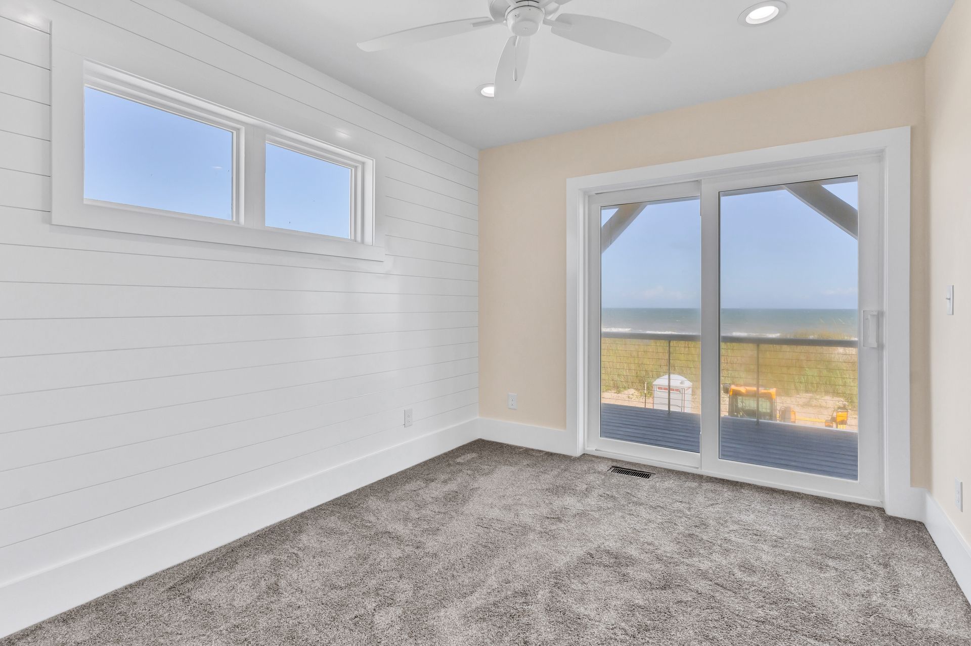 An empty room with sliding glass doors and a ceiling fan.