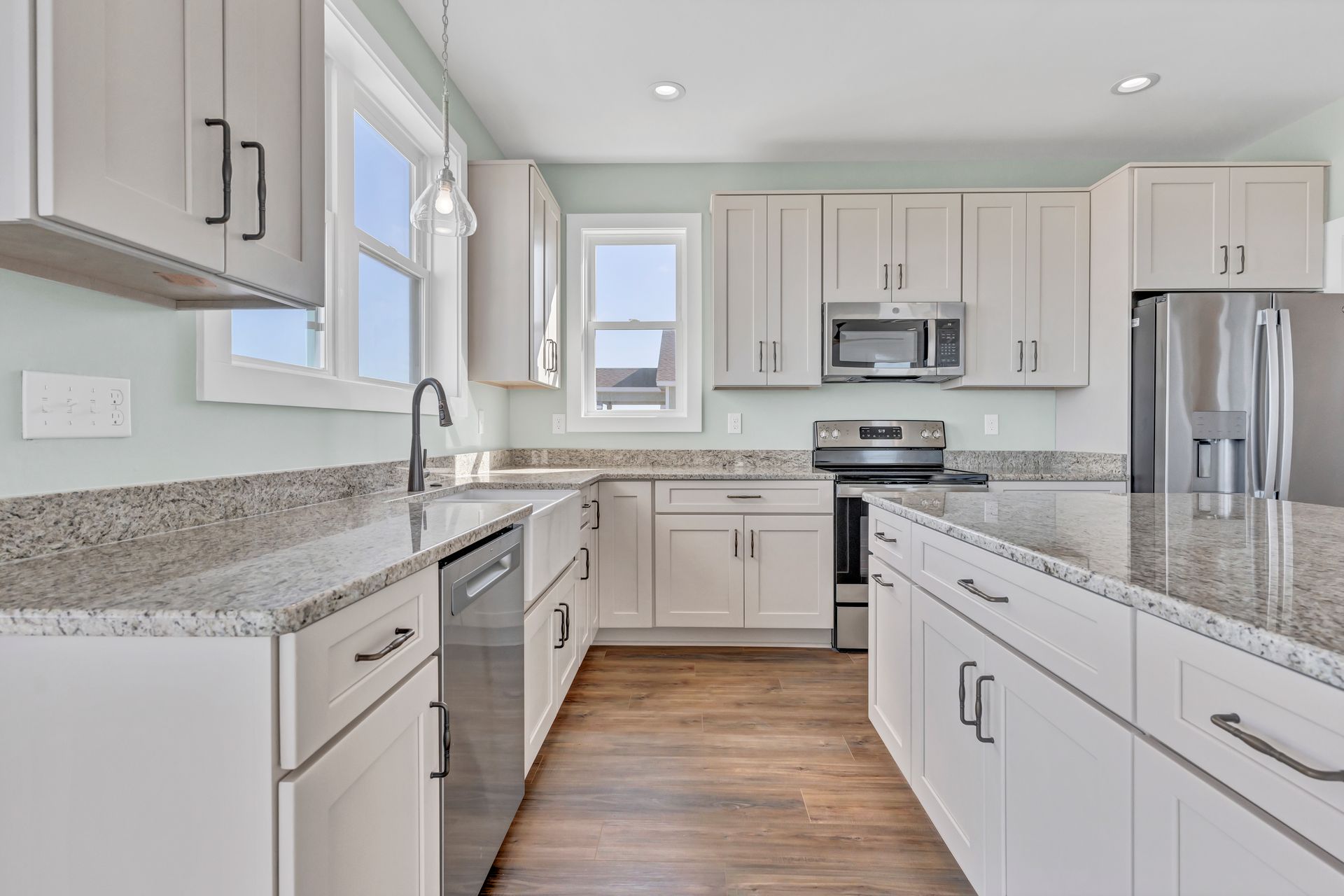 A kitchen with white cabinets , granite counter tops , and stainless steel appliances.