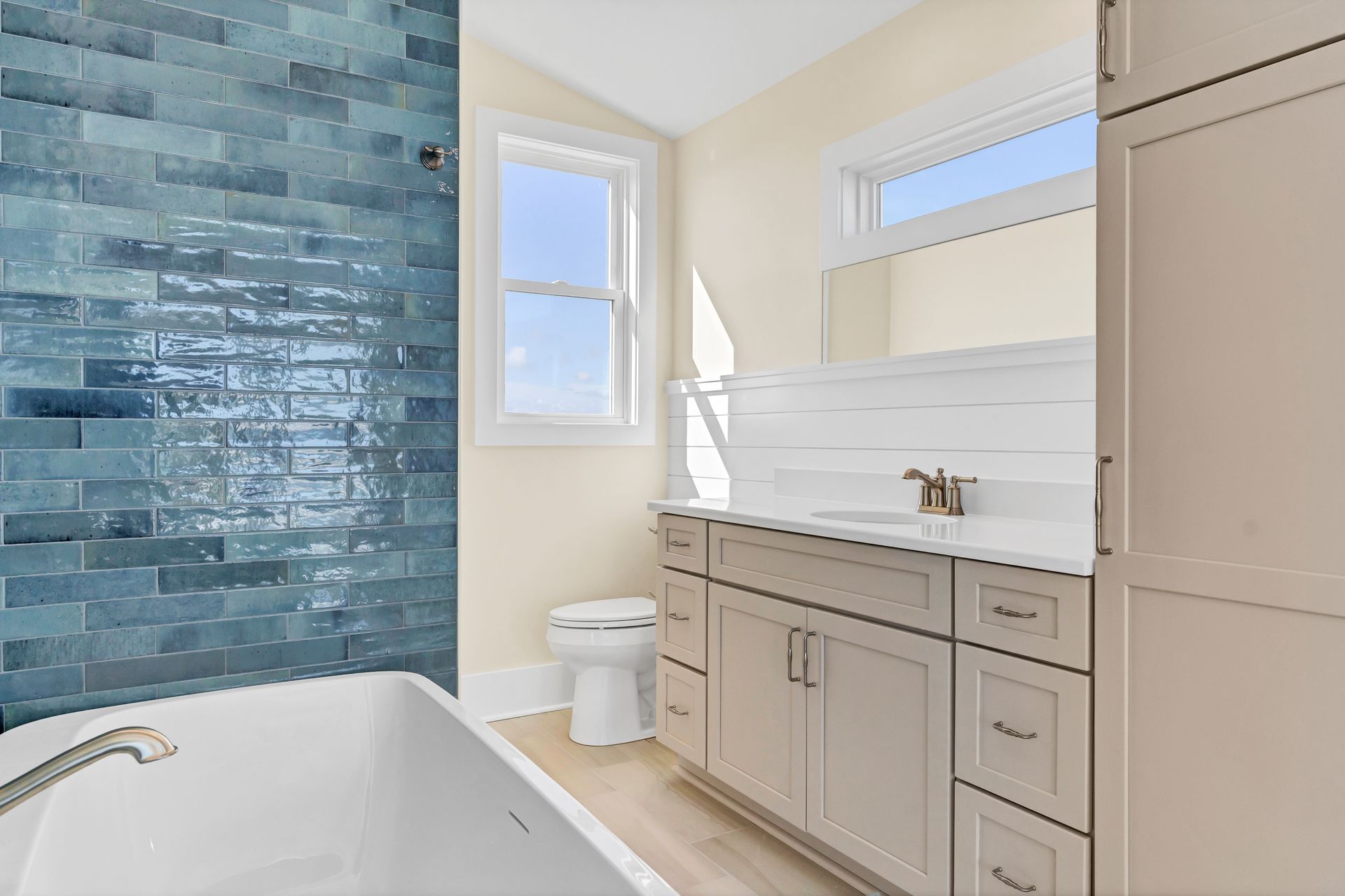 A bathroom with a tub , sink , toilet and window.