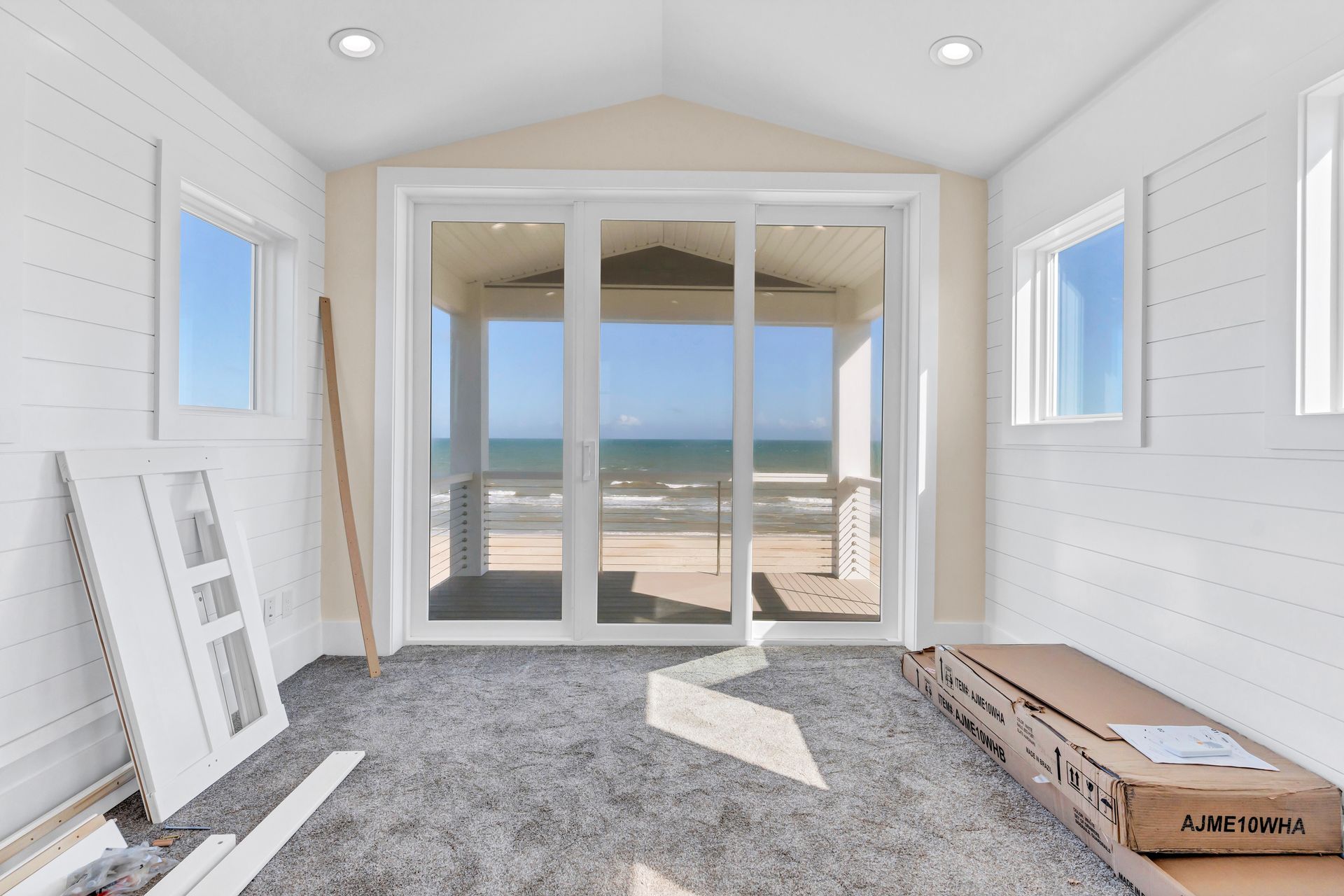 A room with sliding glass doors and a view of the ocean.
