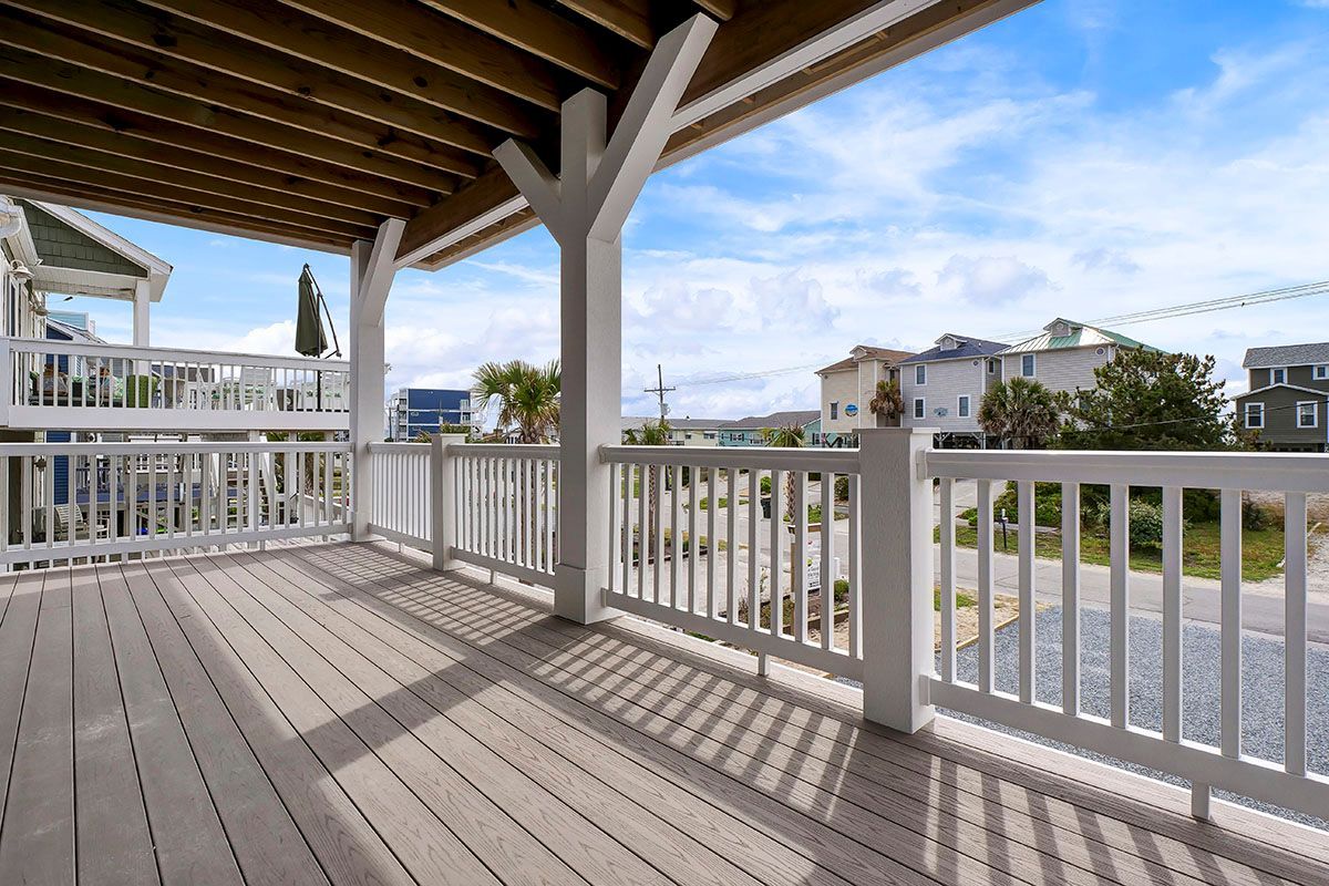 A large deck with a white railing and a view of the ocean