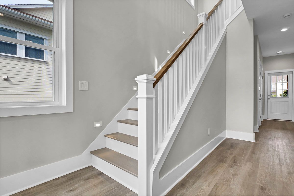 A white staircase with wooden steps and a wooden railing in a hallway