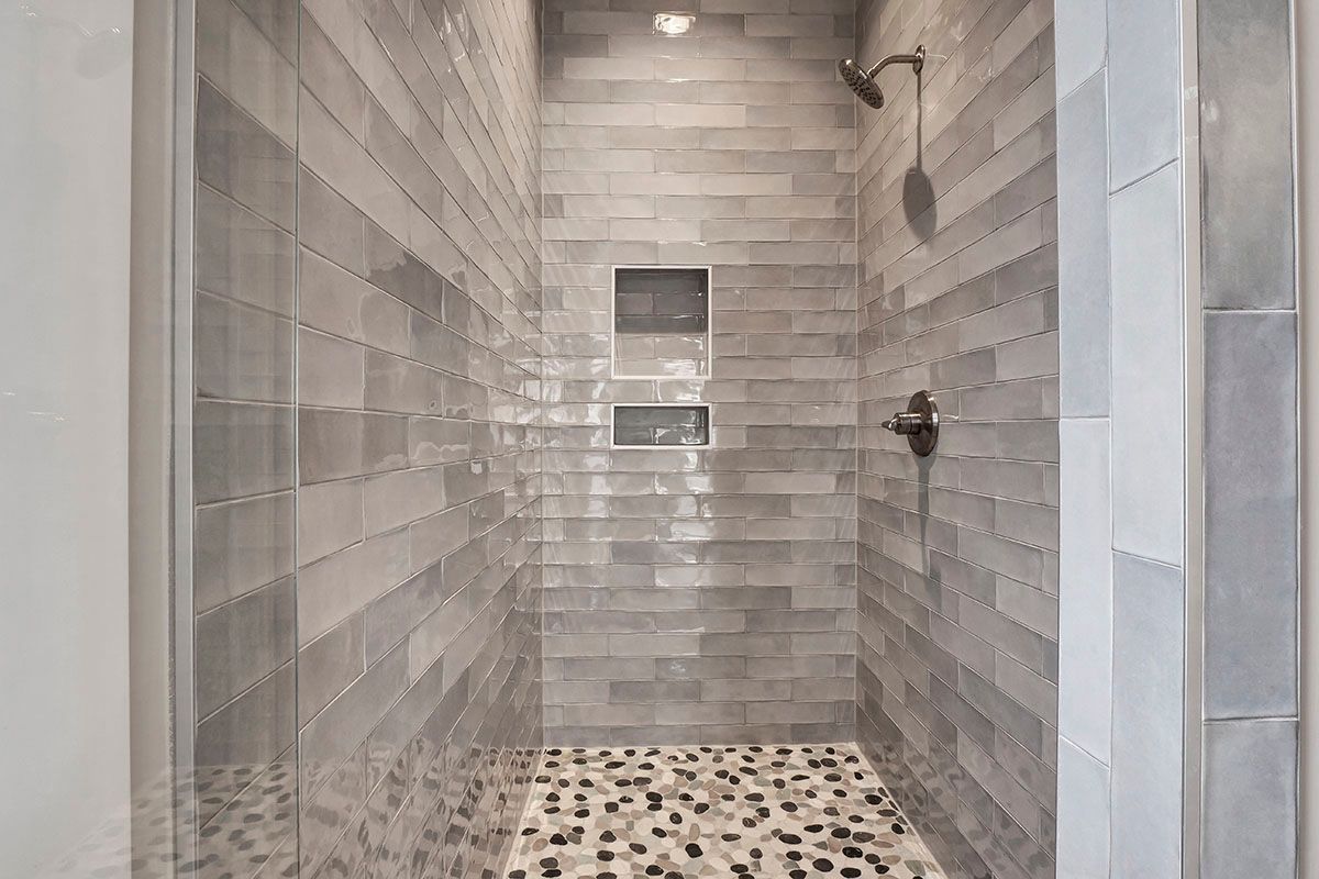 A walk-in shower with a tiled floor and a glass door