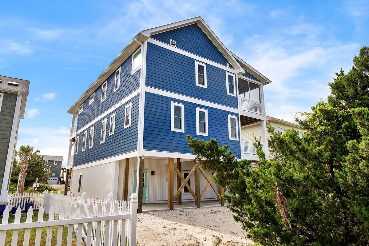 A blue and white house with a white fence in front of it