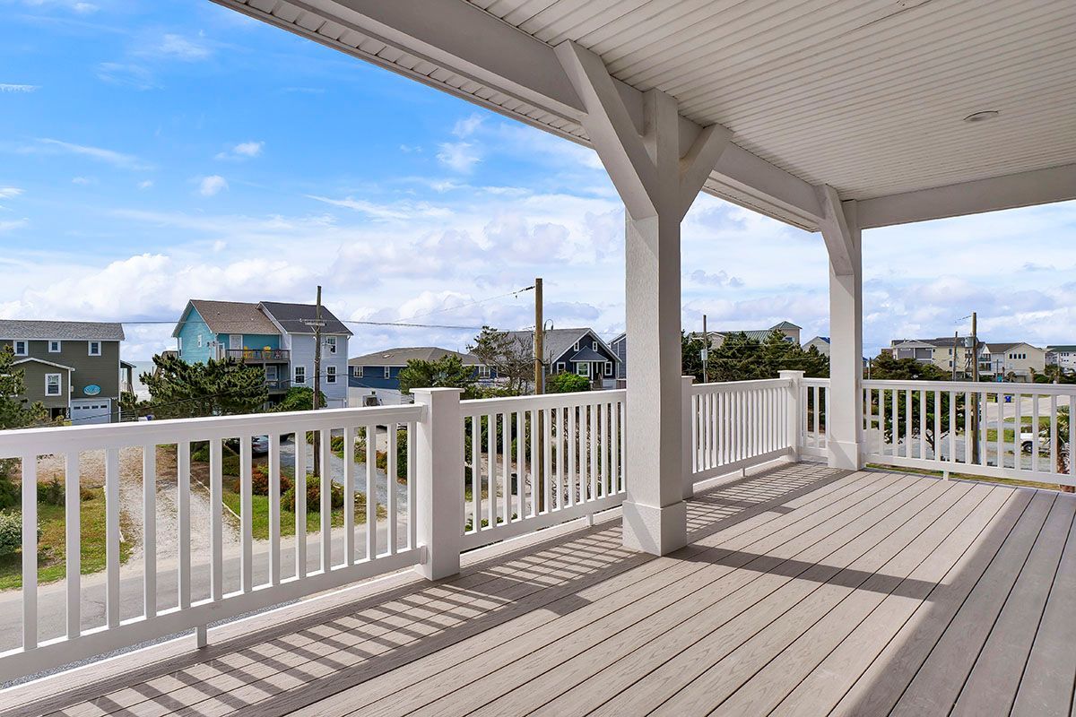 A large deck with a white railing and a view of the ocean