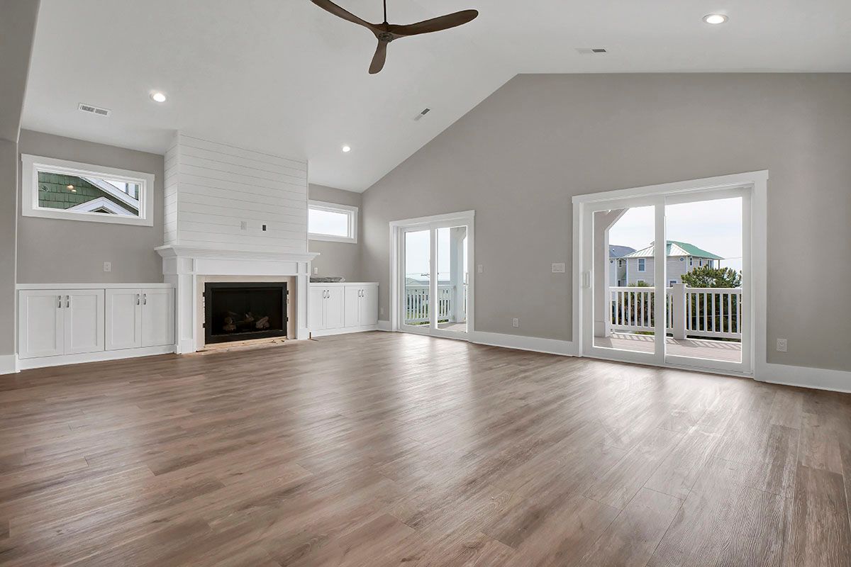 An empty living room with shiny hardwood floors and a fireplace