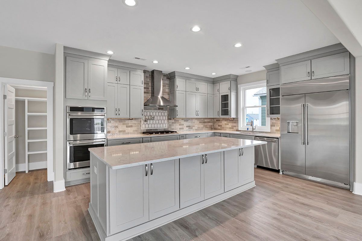 A kitchen with white cabinets, stainless steel appliances, and a large island