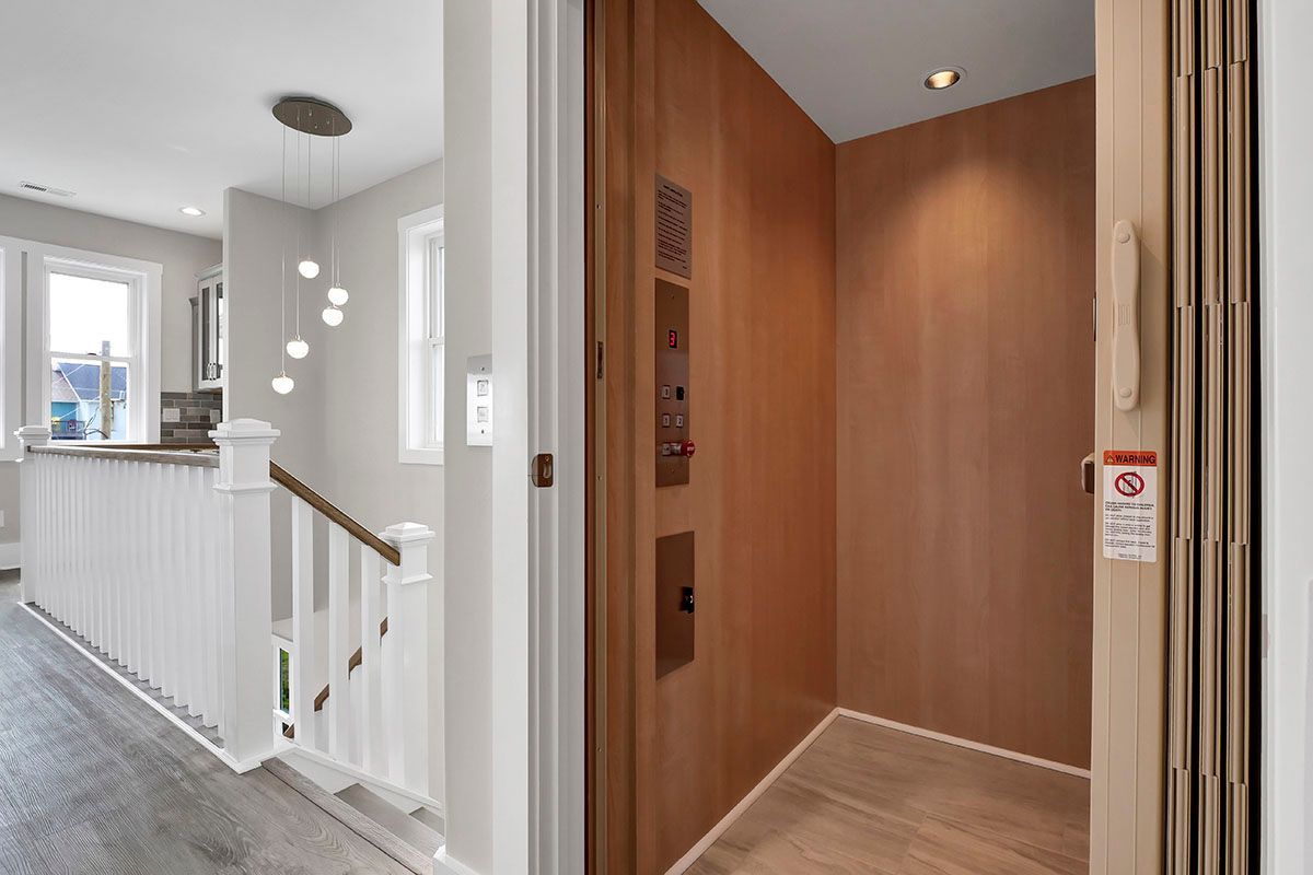 A wooden elevator in a house next to a staircase