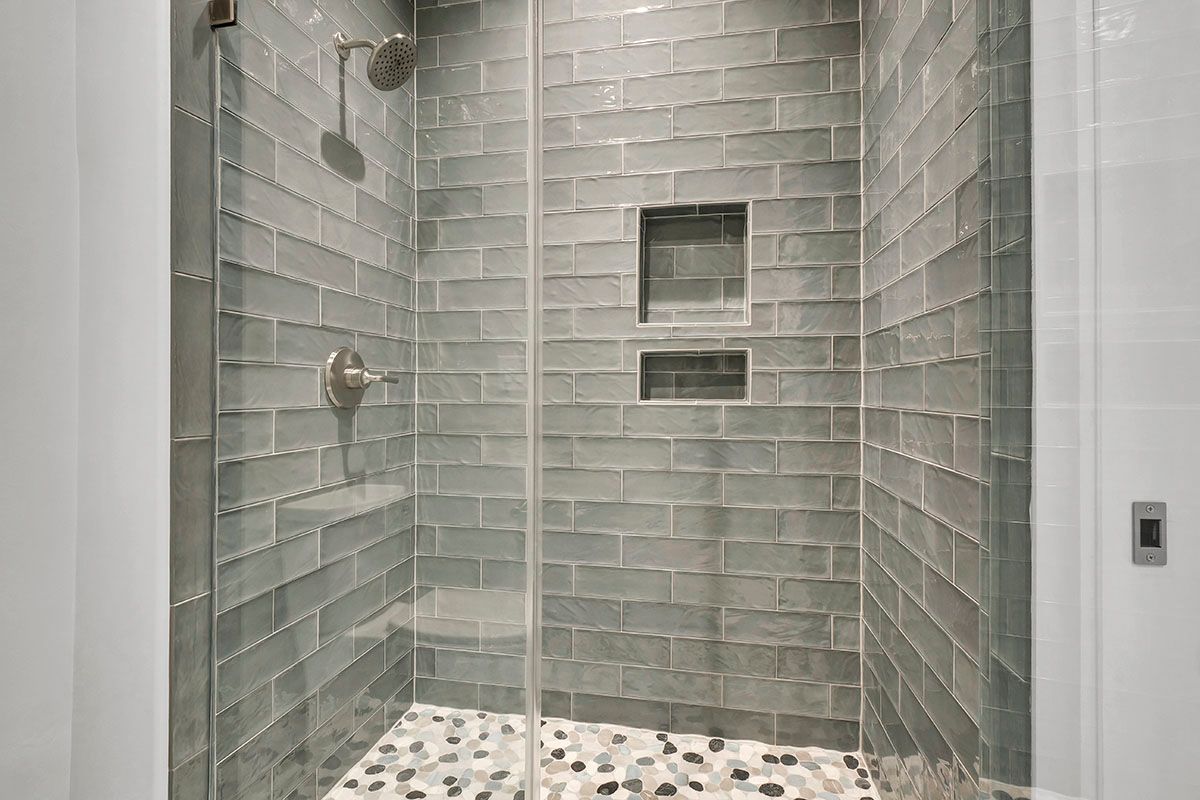 A walk-in shower with a glass door and brick tiles