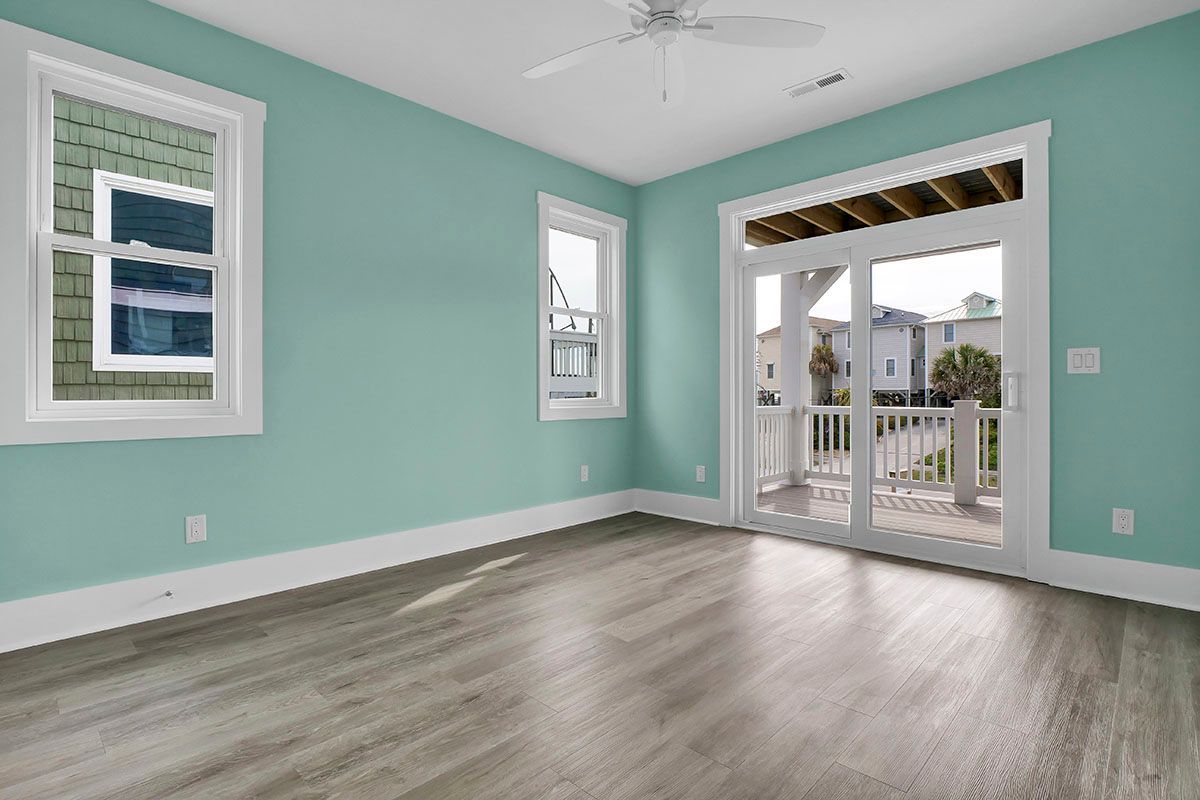 An empty room with a ceiling fan and sliding glass doors