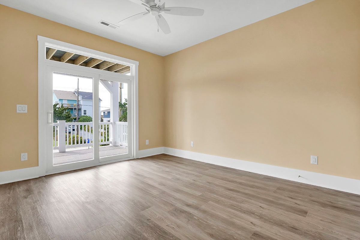 An empty living room with hardwood floors and a ceiling fan