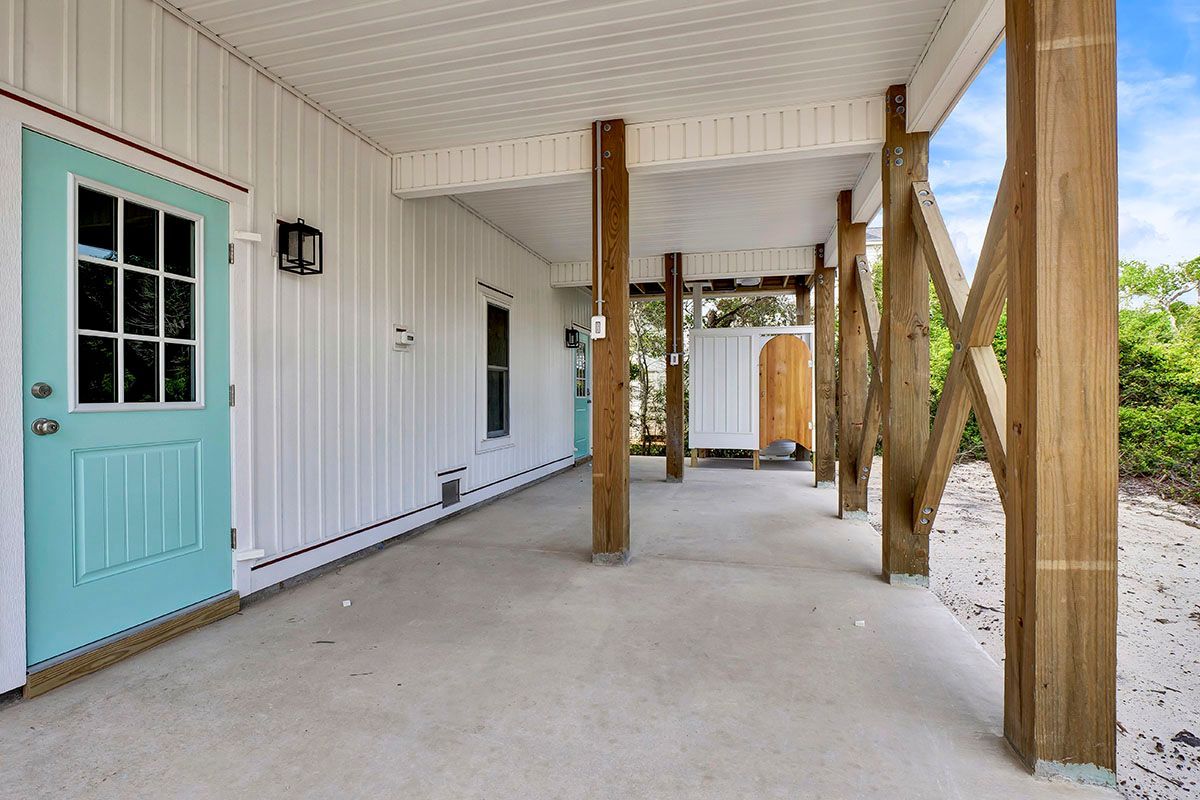 A white house with a blue door and a covered porch
