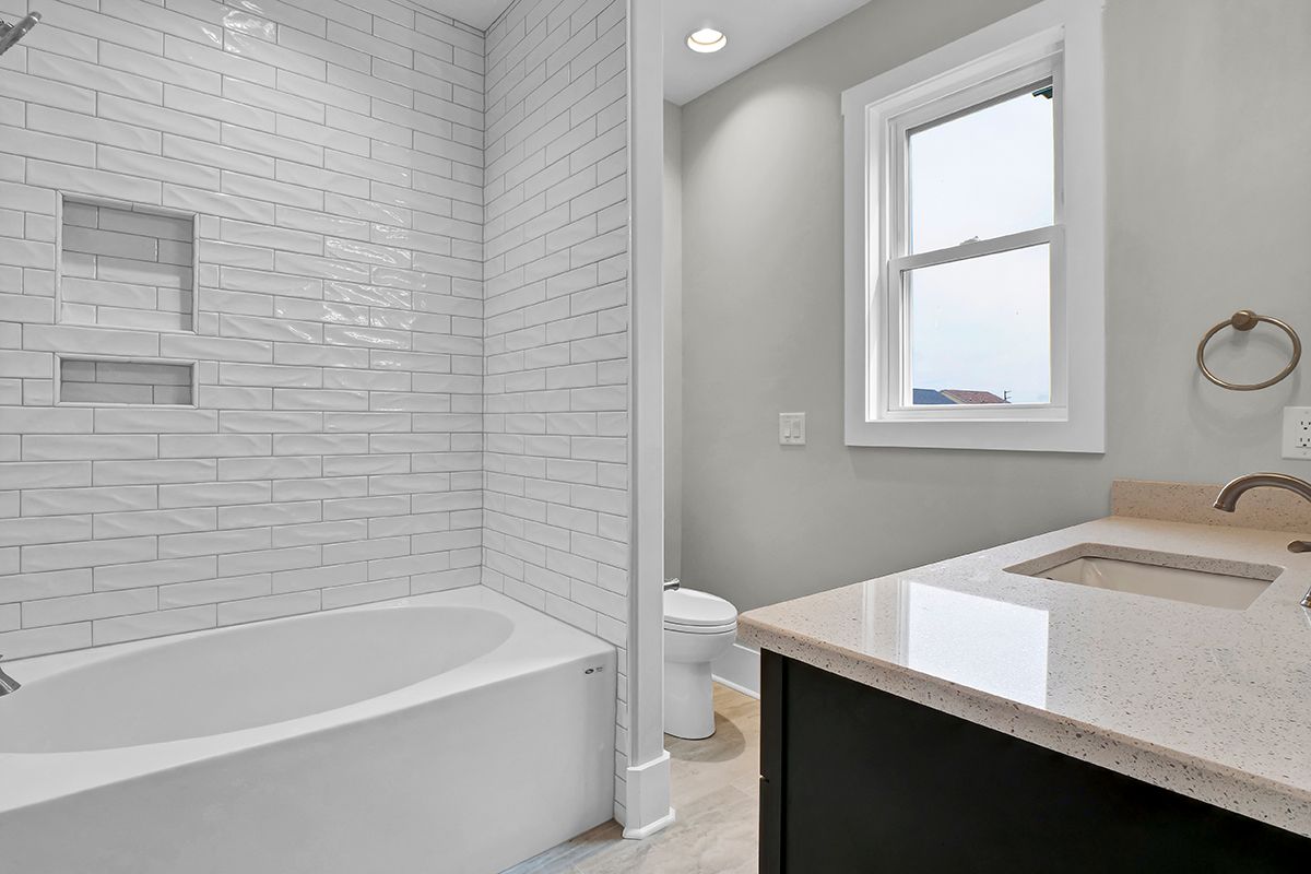 A bathroom with a tub, sink, toilet and shower