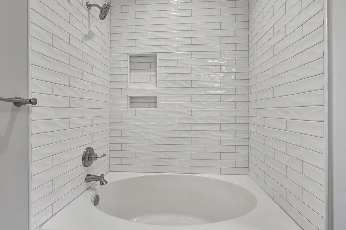 A bathroom with white brick walls and a bathtub