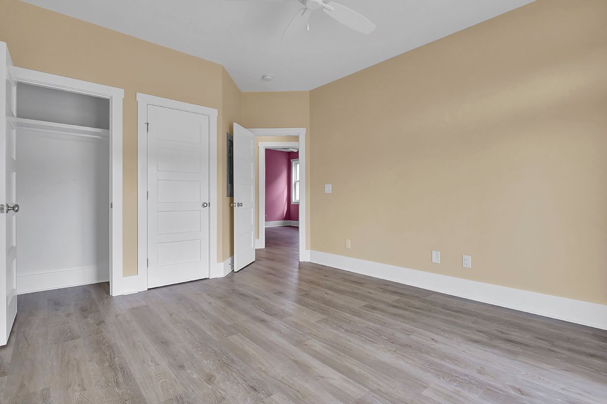 An empty bedroom with hardwood floors and a ceiling fan