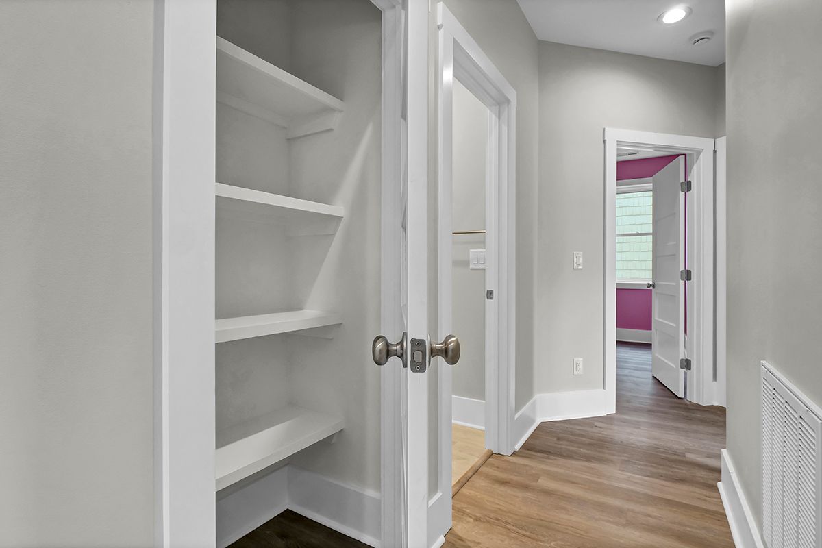 A hallway with a closet and a door leading to a bedroom