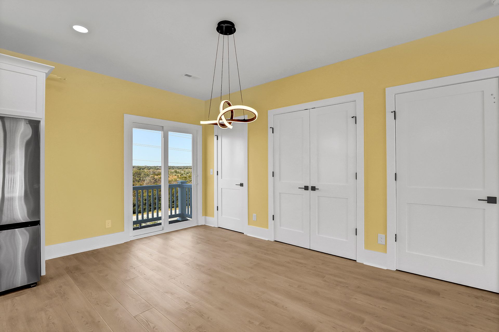 An empty room with yellow walls, hardwood floors, and white doors