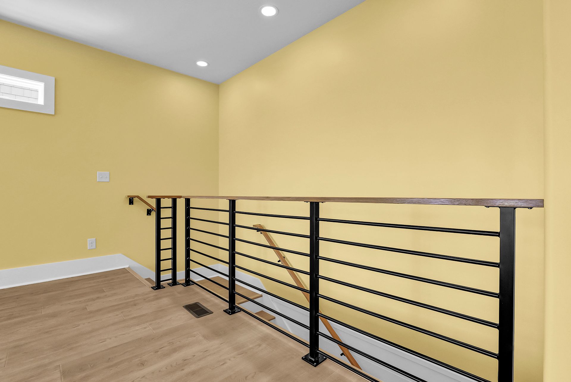 An empty room with yellow walls and a black railing