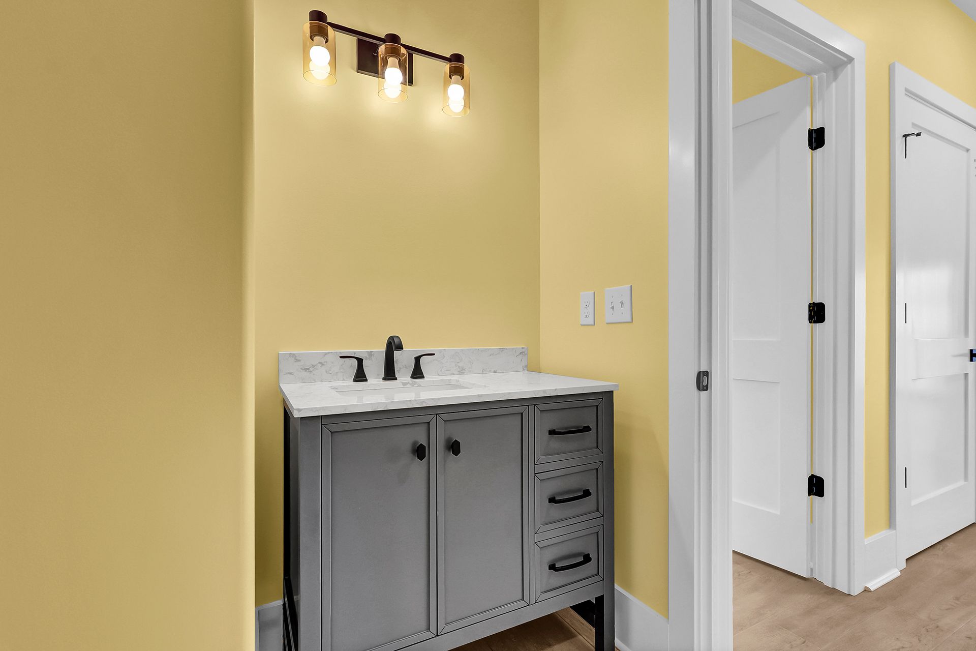 A bathroom with yellow walls and a gray vanity with a sink