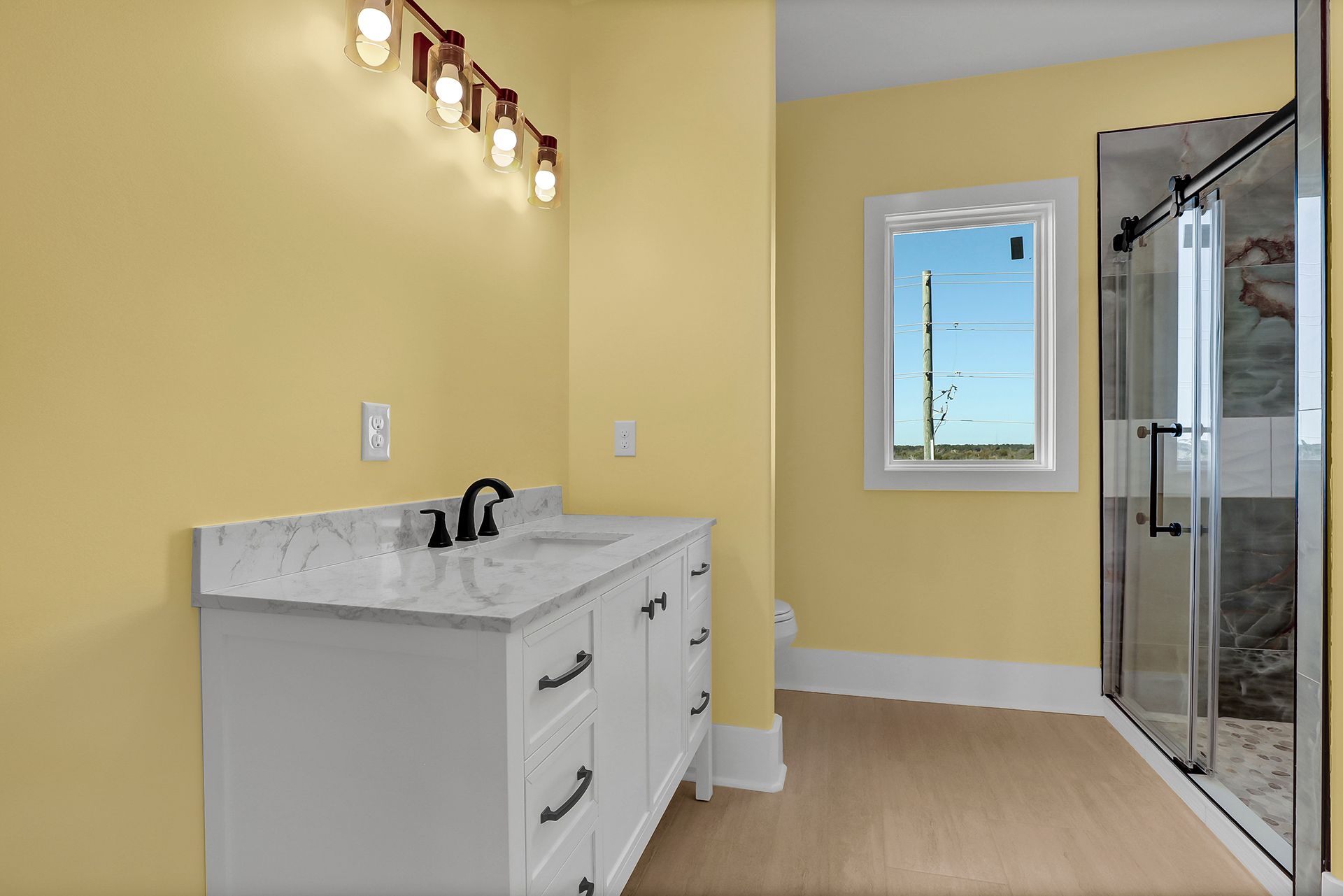 A bathroom with a sink, shower, and window