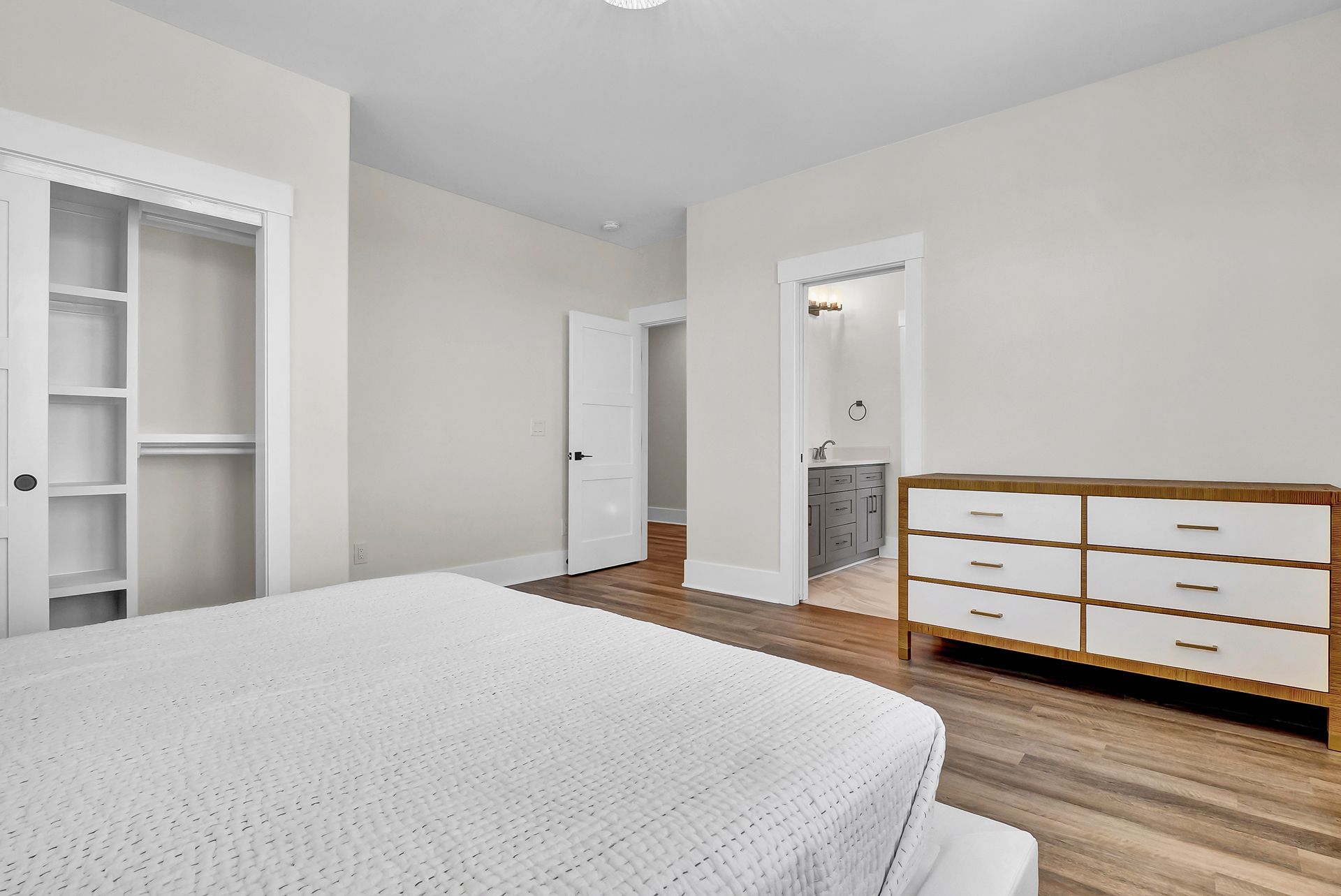 A bedroom with a bed, dresser, and closet