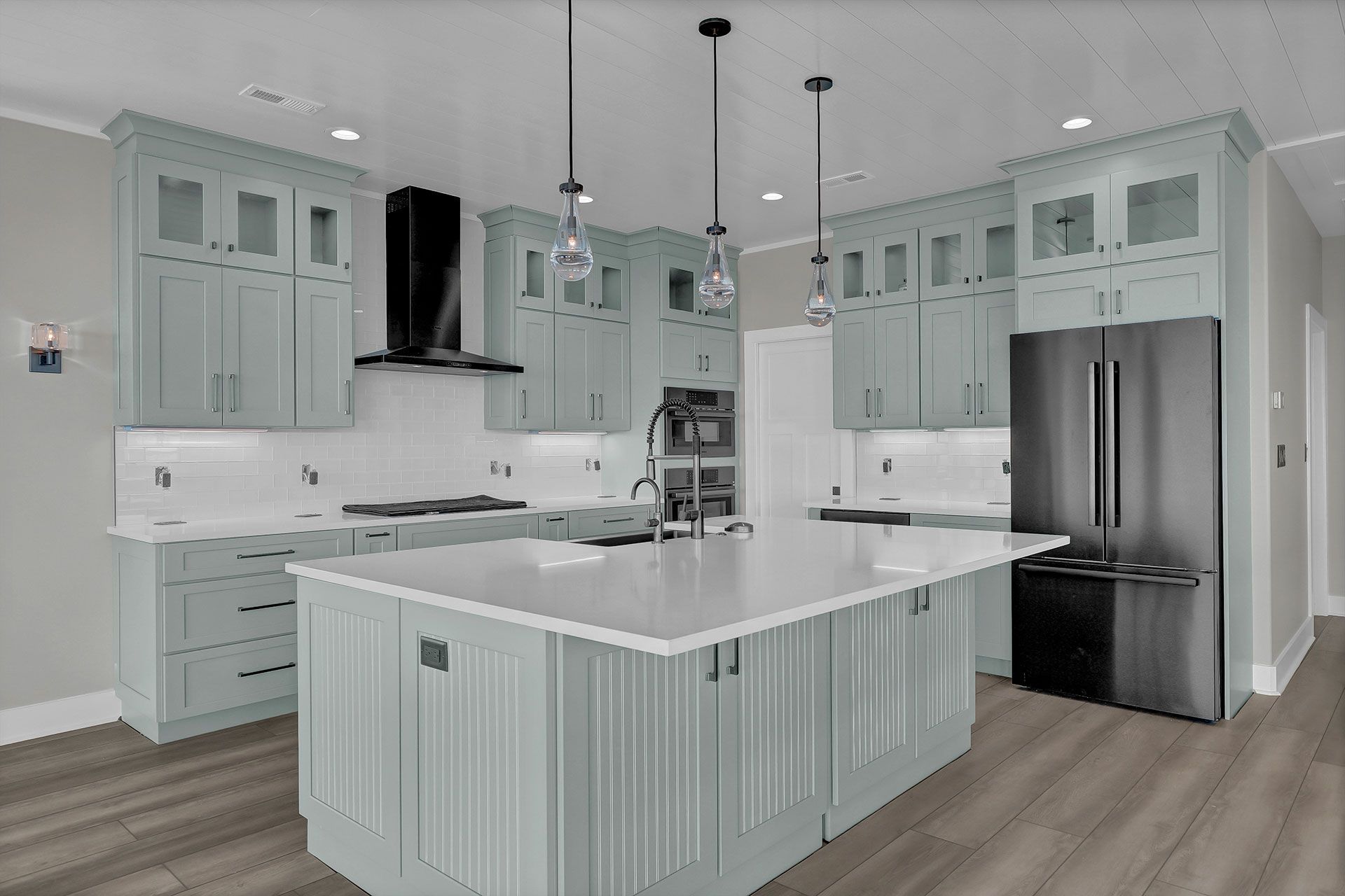 A modern kitchen with light blue cabinets, white countertops, and a large island.