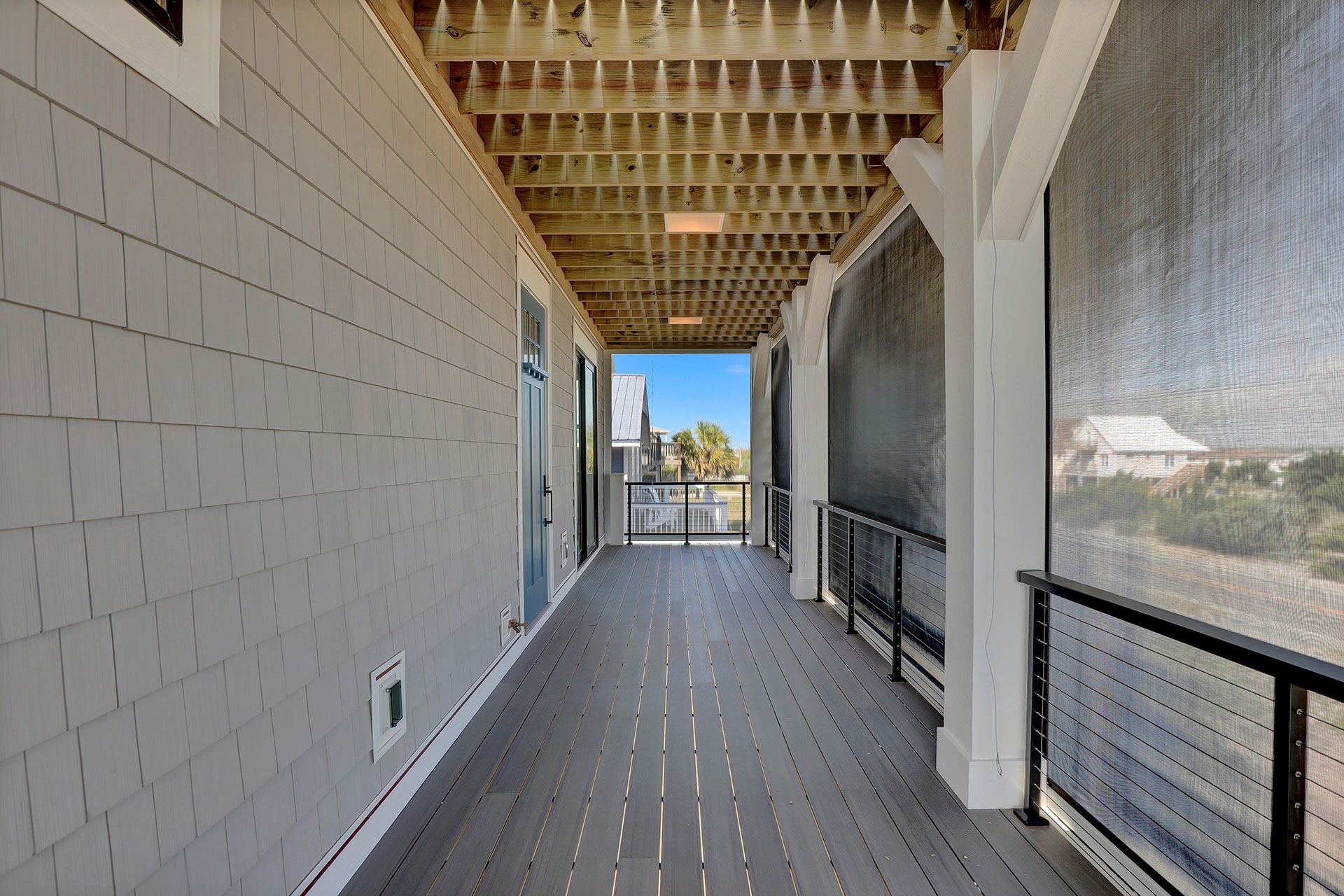 Covered porch with gray siding, wooden deck, and ocean views.