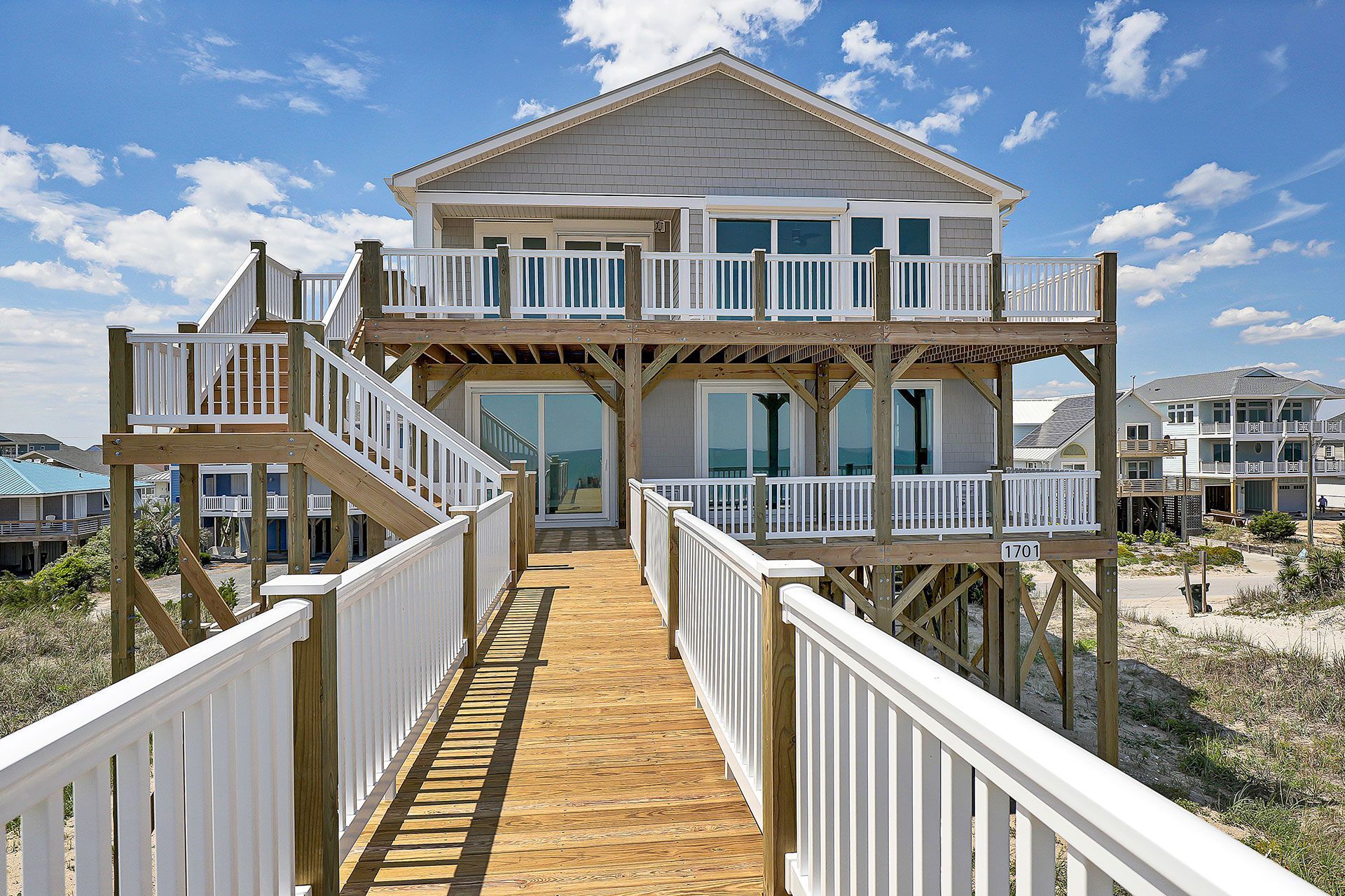 Beach house with wooden deck and boardwalk leading to it.