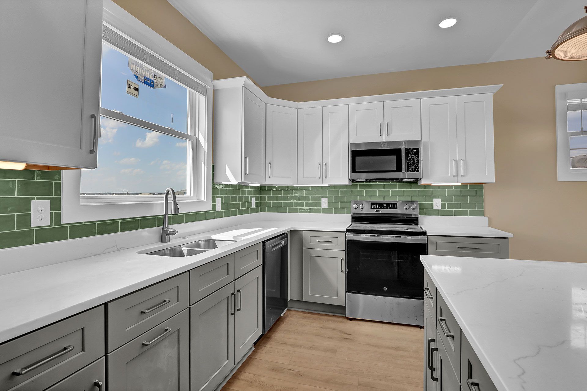 Modern kitchen with gray and white cabinets, green backsplash, and a stainless steel stove.