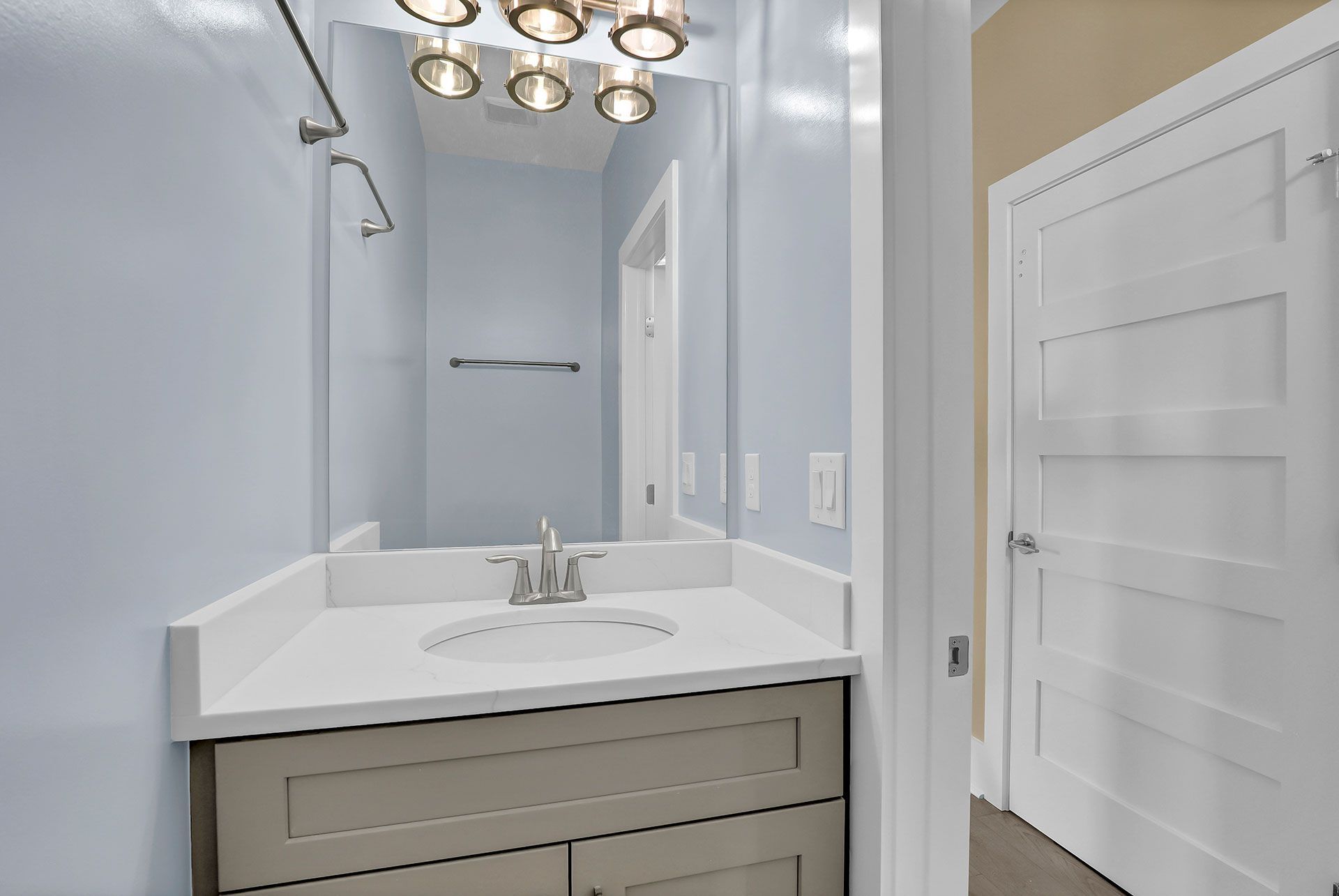 Bathroom with light blue walls, white vanity, and white door.