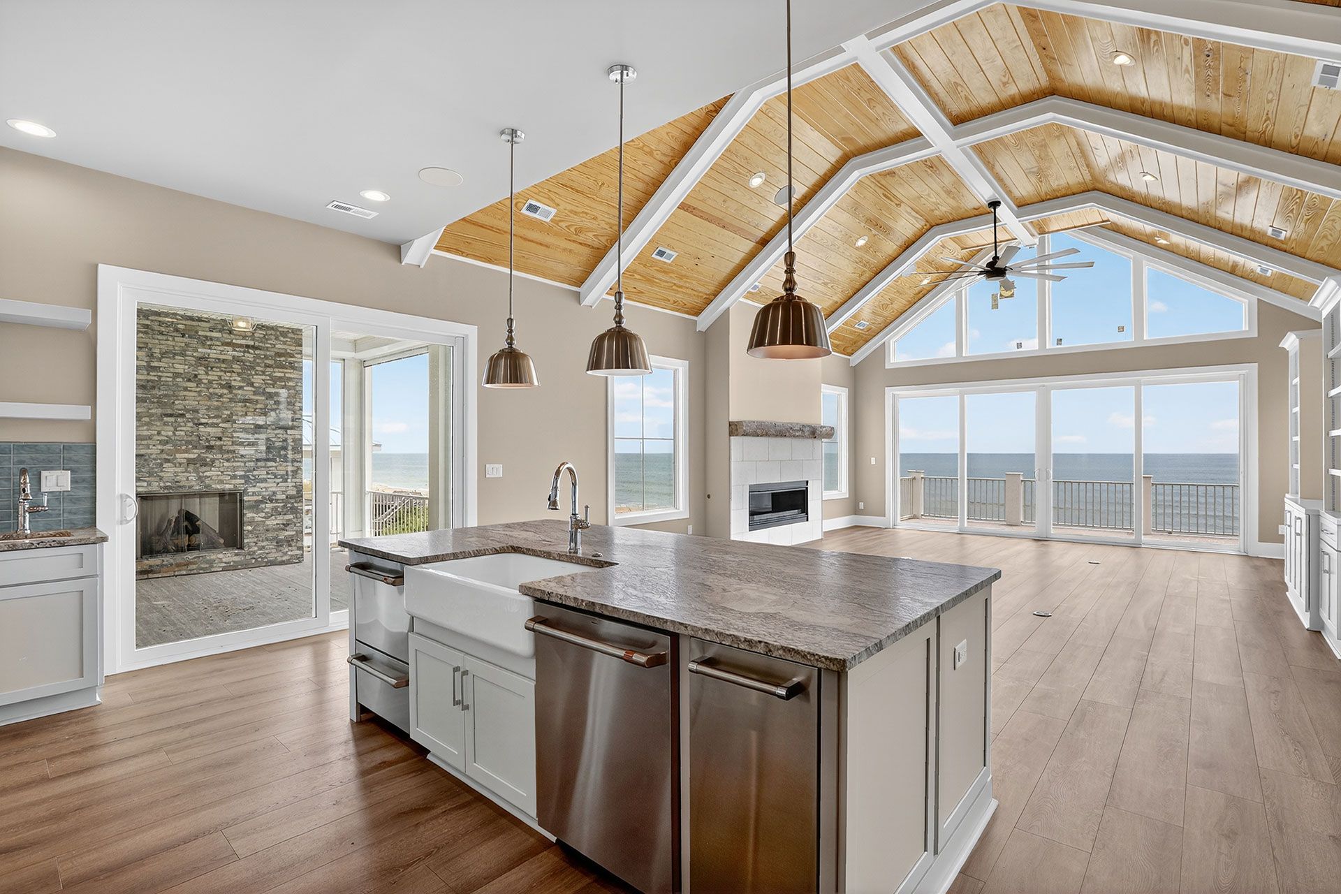 Kitchen with vaulted wood ceiling, island with sink, and ocean view.