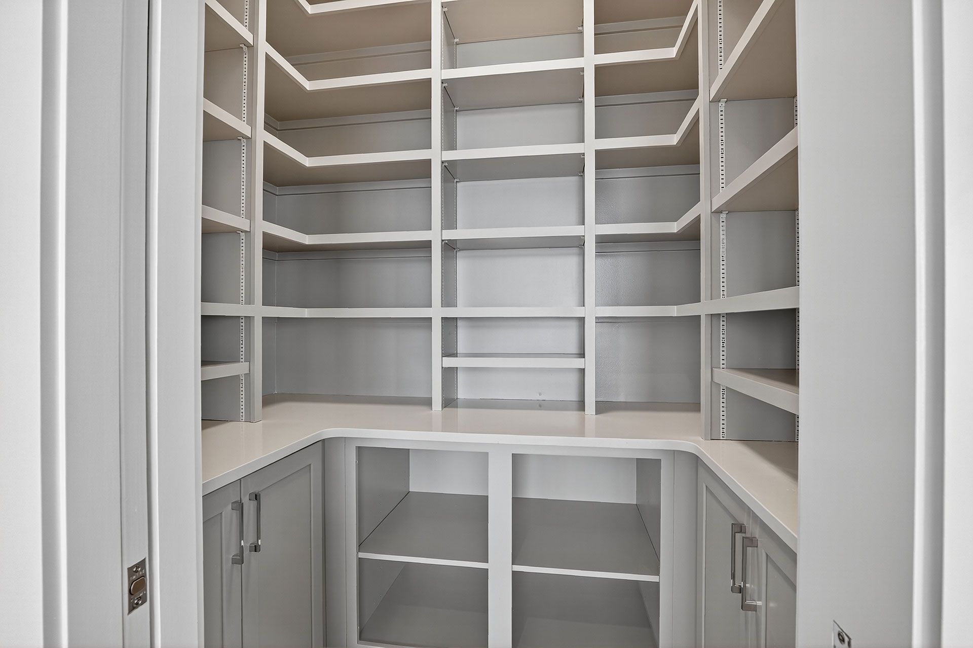 Empty, built-in pantry with white shelves and lower cabinets.
