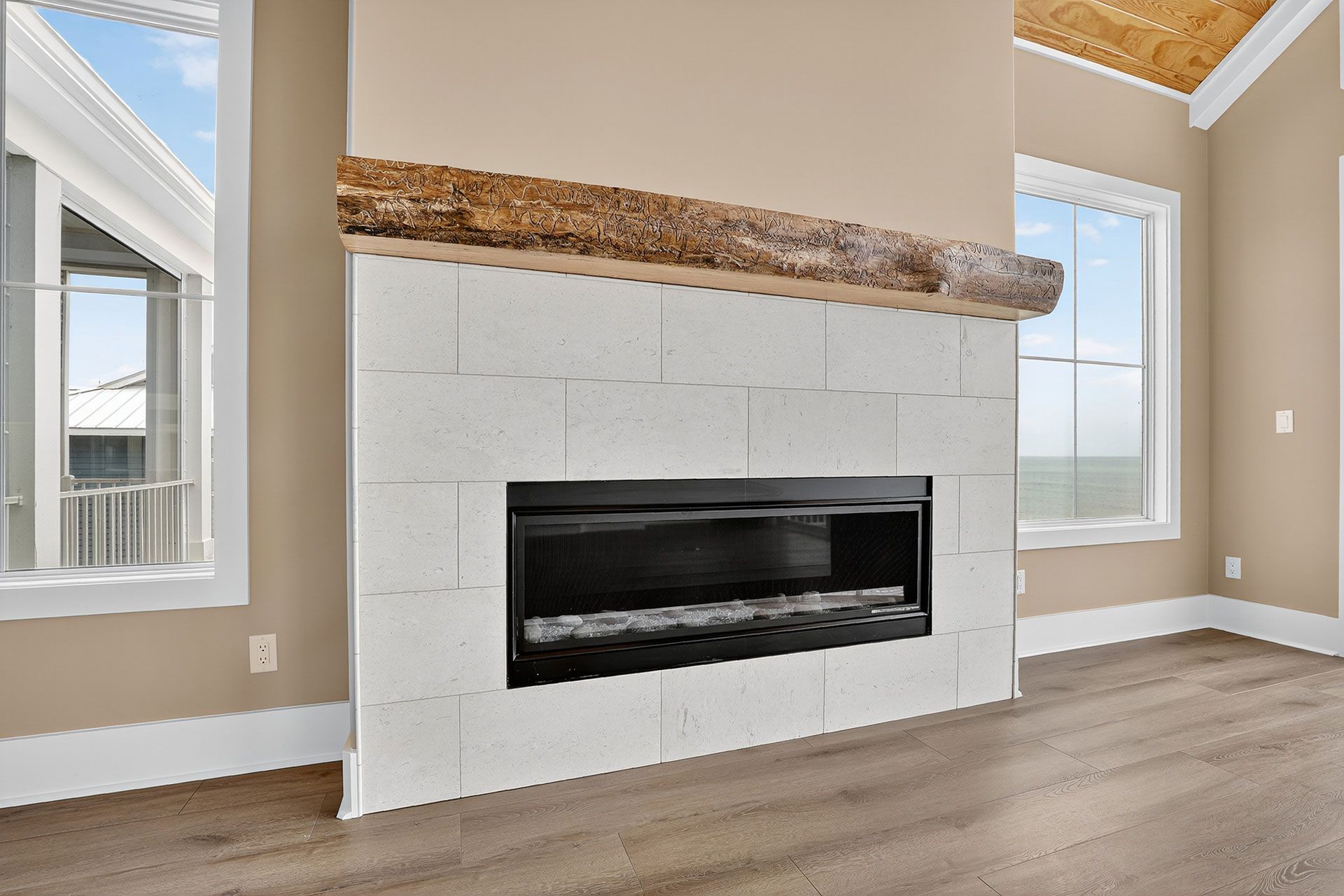 Fireplace with white brick surround, black firebox, and wooden mantel. Two windows flank the wall.