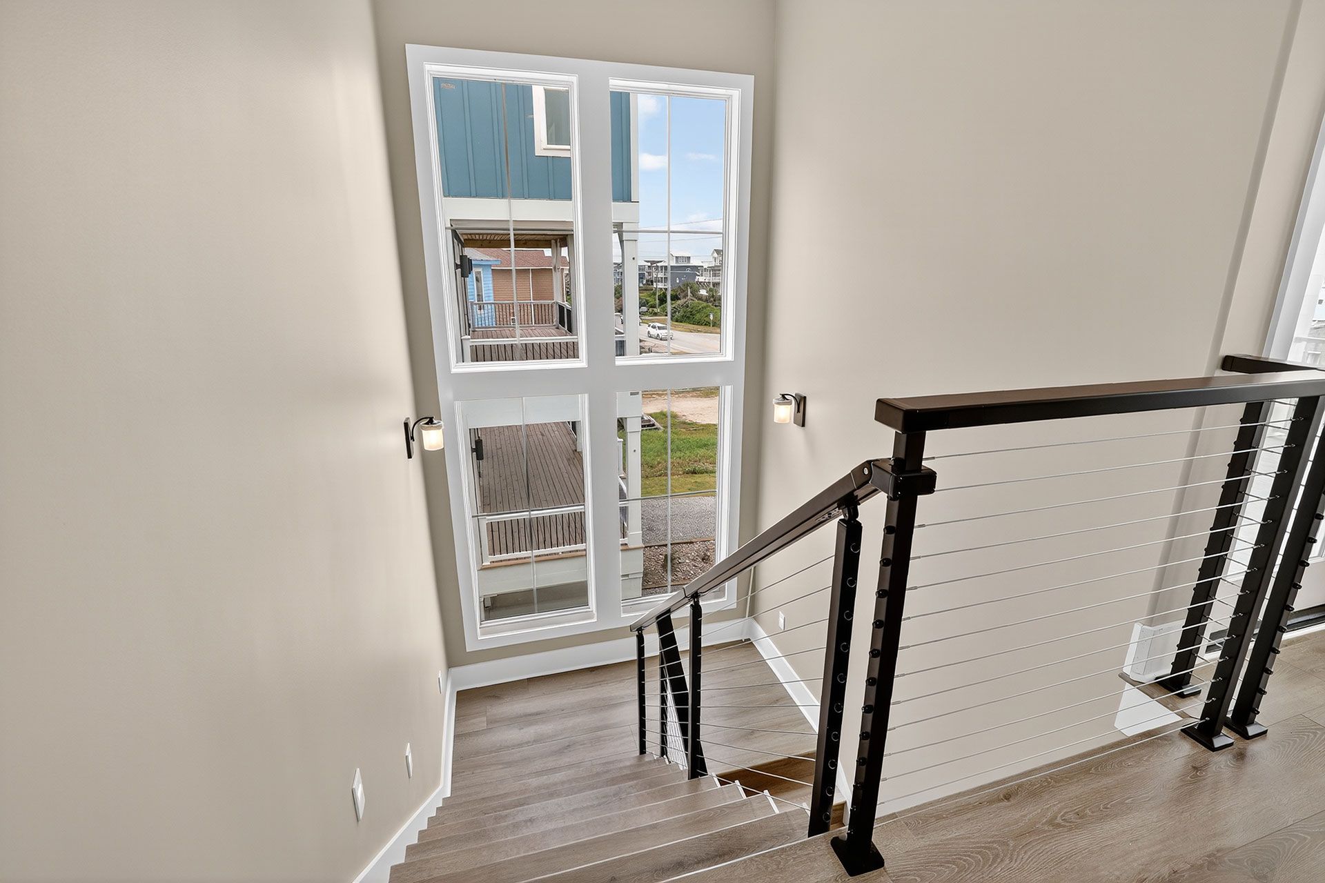 Stairwell with a large window, modern black railing, and neutral-colored walls.